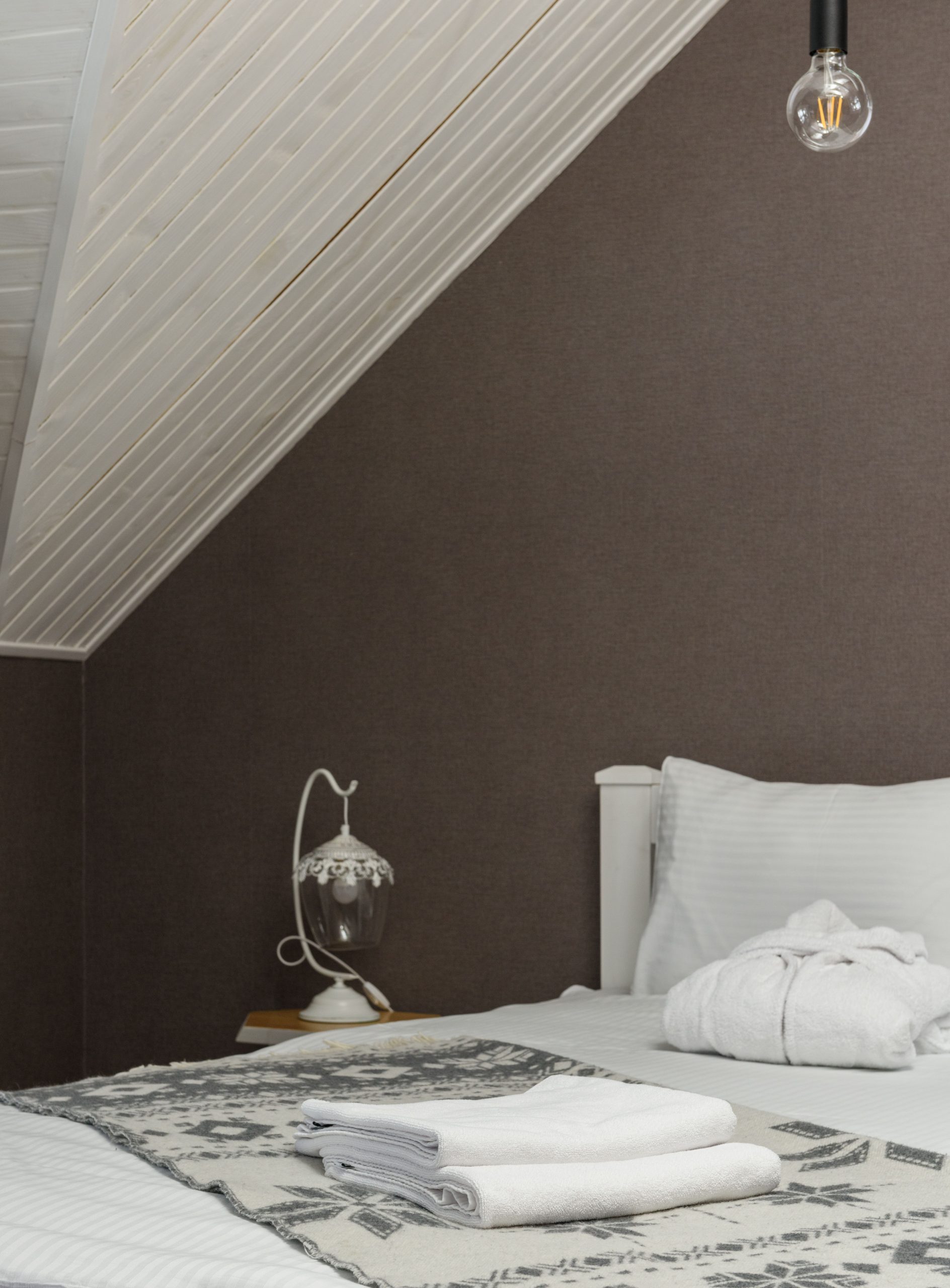 Elegant bedroom interior with neatly arranged bed and vintage lamp, ideal for home design inspiration.