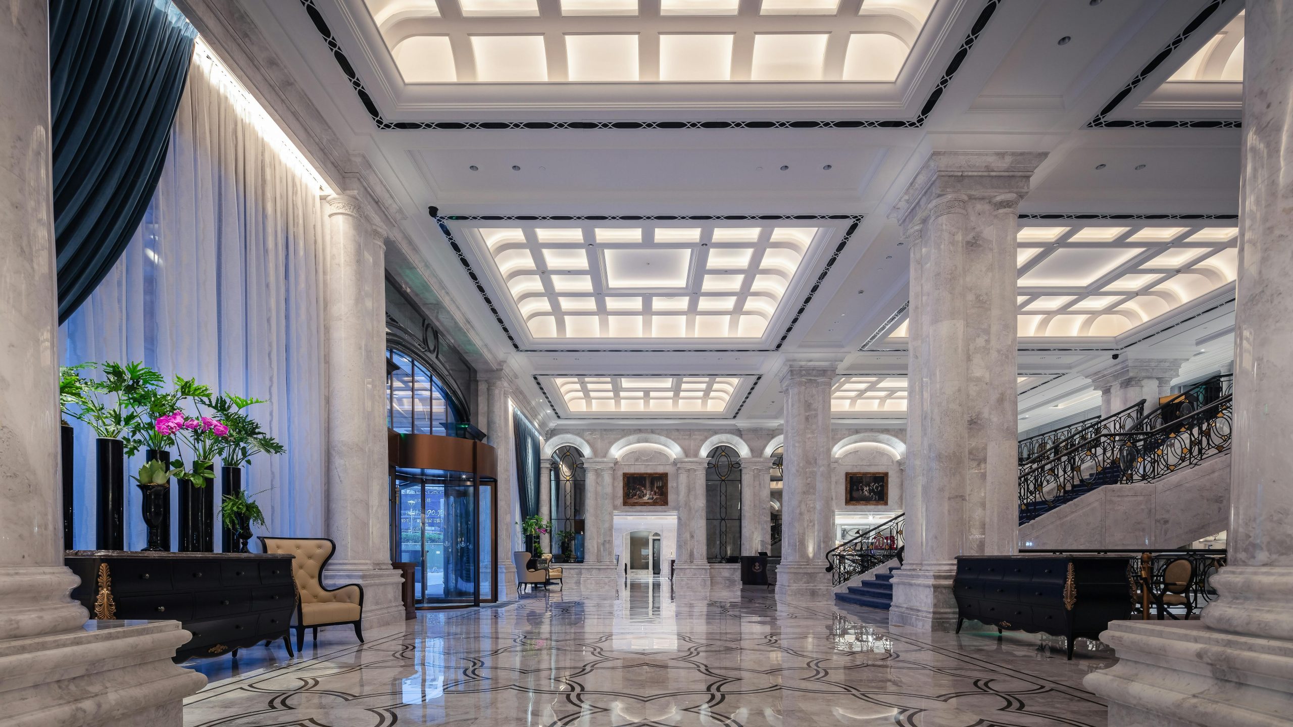 Elegant hotel lobby featuring grand marble columns, high ceiling, and decorative elements in a sophisticated design.