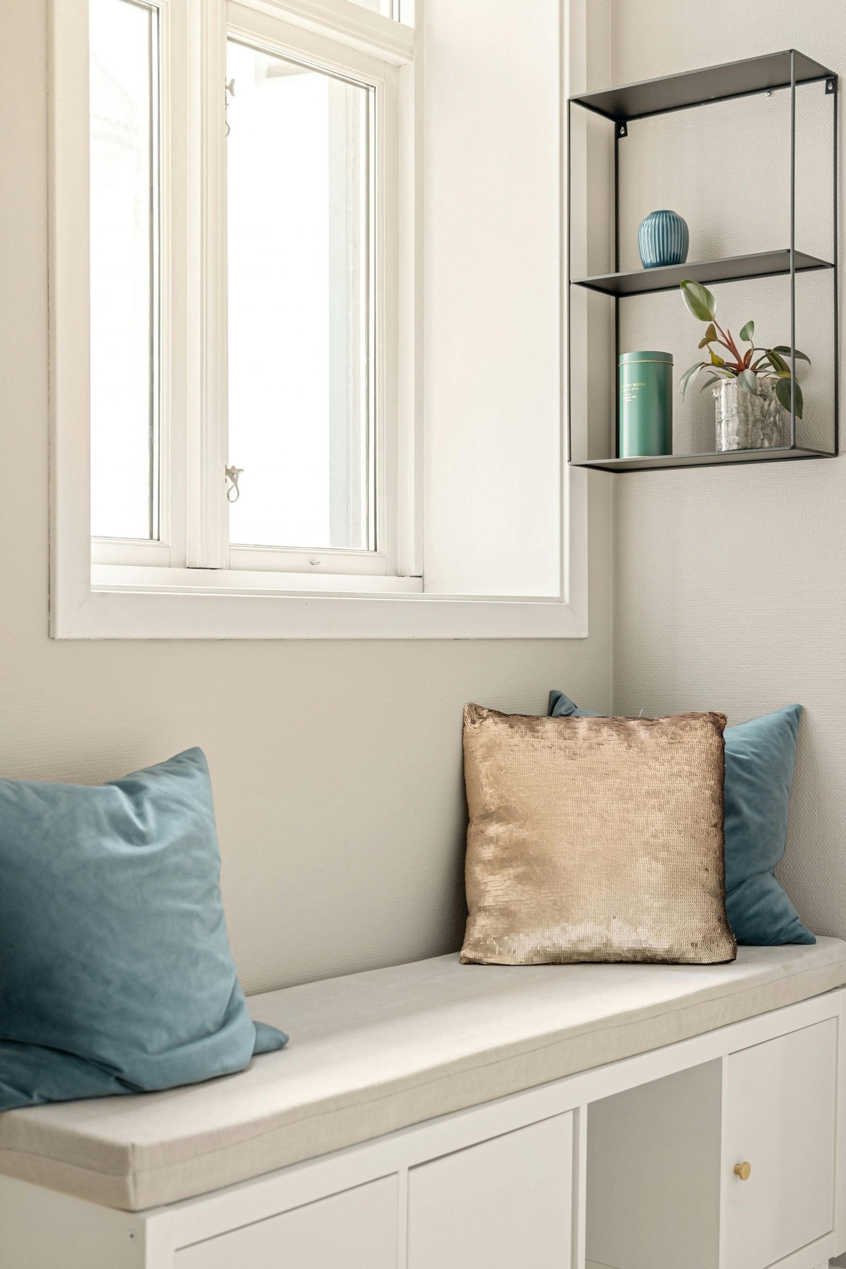 Elegant indoor nook with plush pillows, modern shelving, and soft natural light.