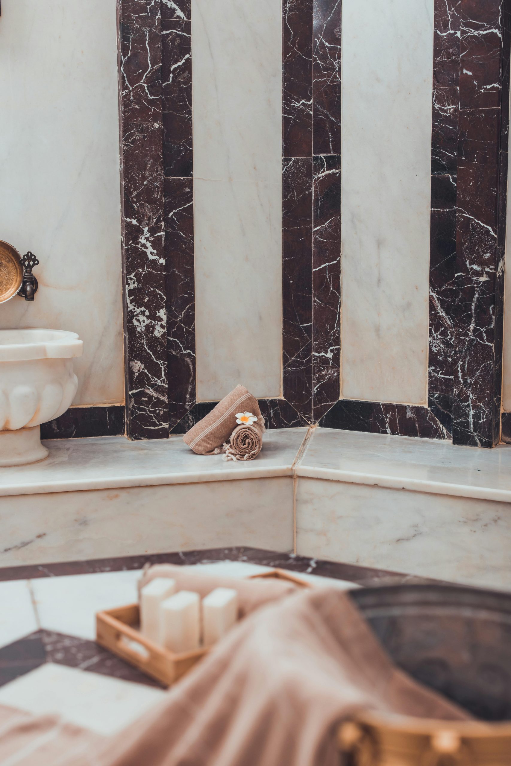 Elegant Turkish bath with marble walls, towel, and candles for a luxurious spa experience.