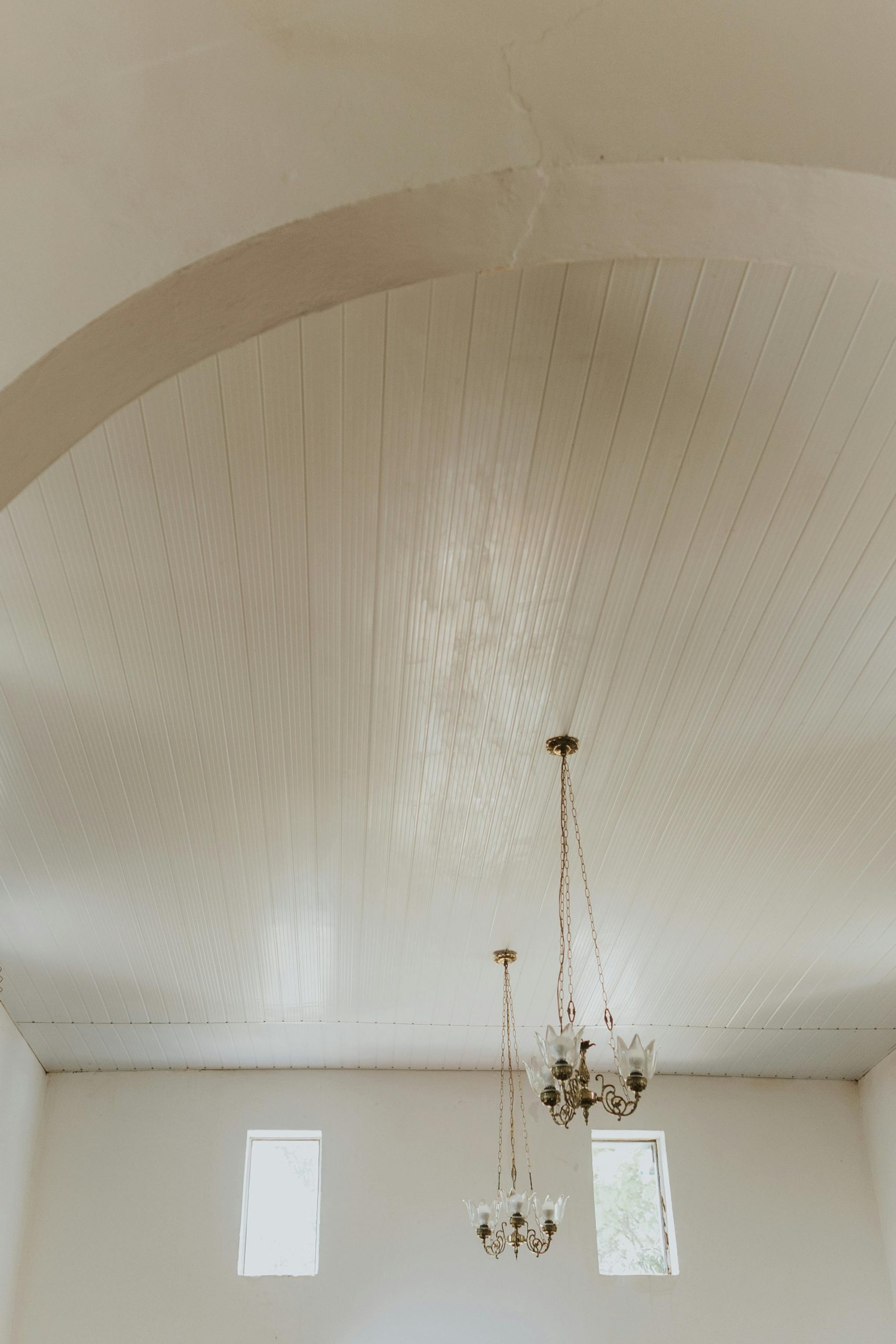 Elegant white arched ceiling with hanging chandeliers and natural light through windows.