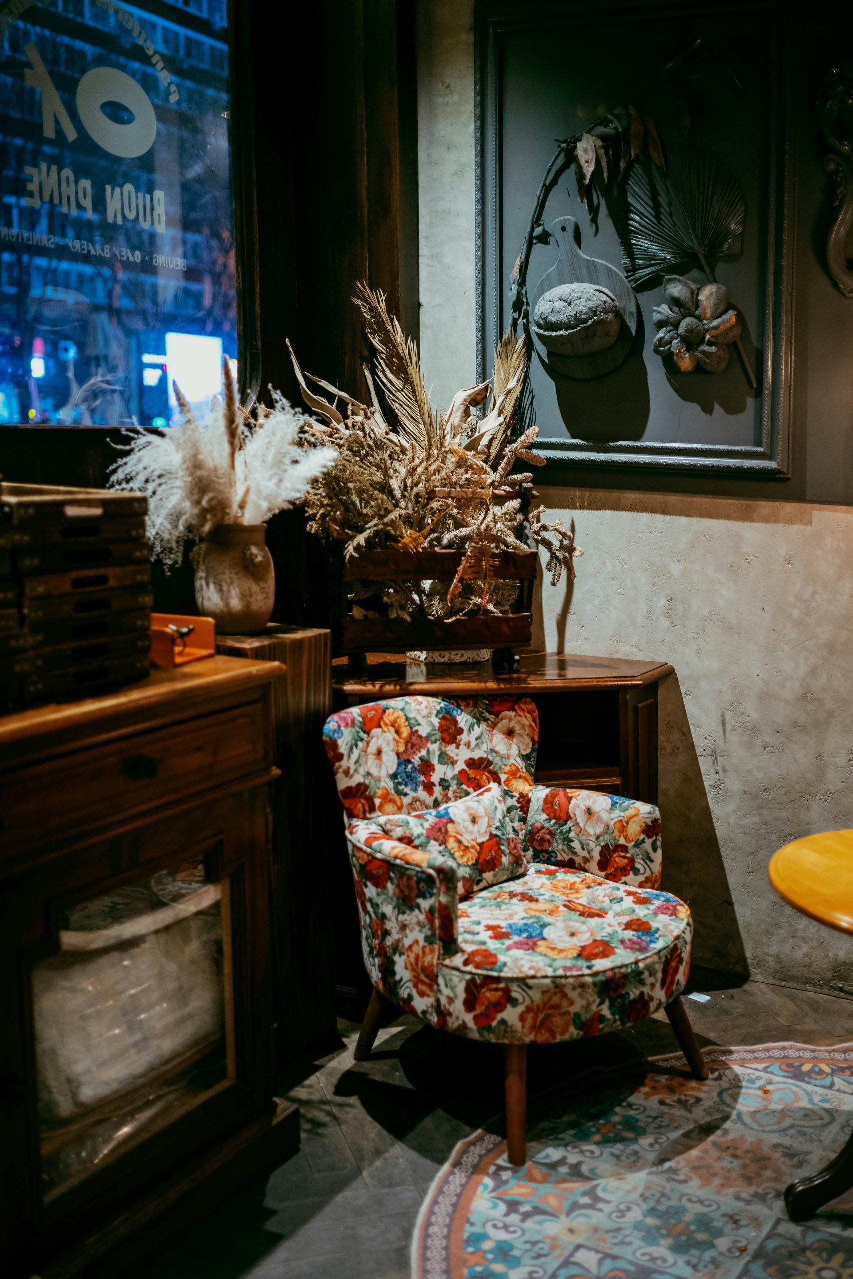 Floral armchair with dried flowers and wooden furniture.
