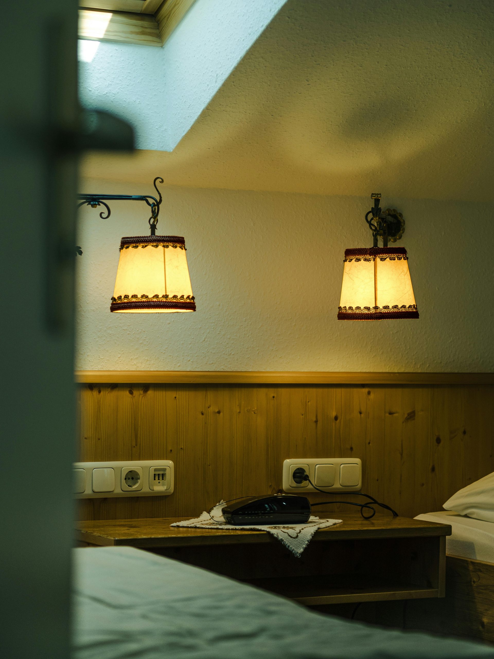 Intimate attic bedroom with soft lighting, wooden walls, and a vintage phone.