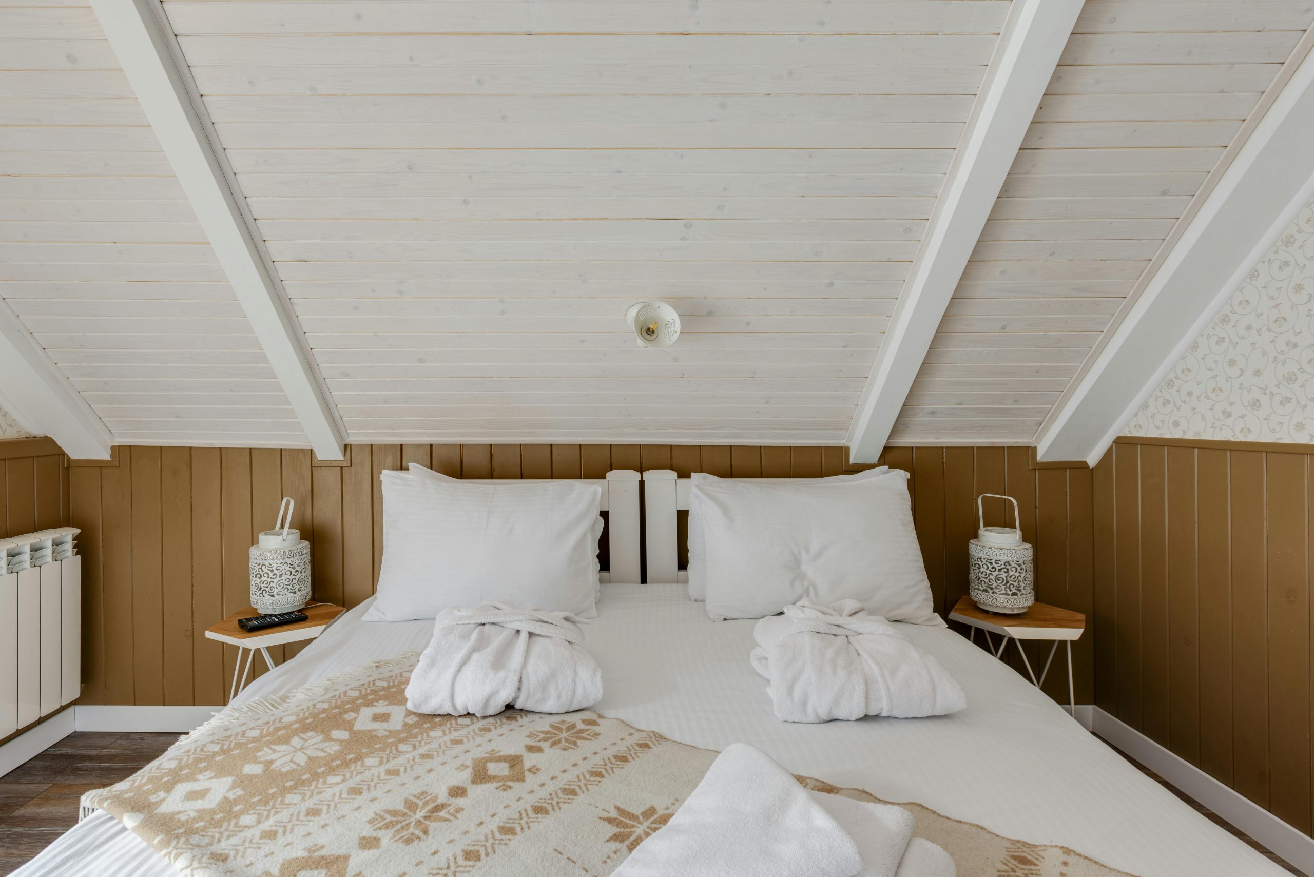 Inviting attic bedroom with cozy bedding and bathrobes on a white bed, perfect for relaxation.