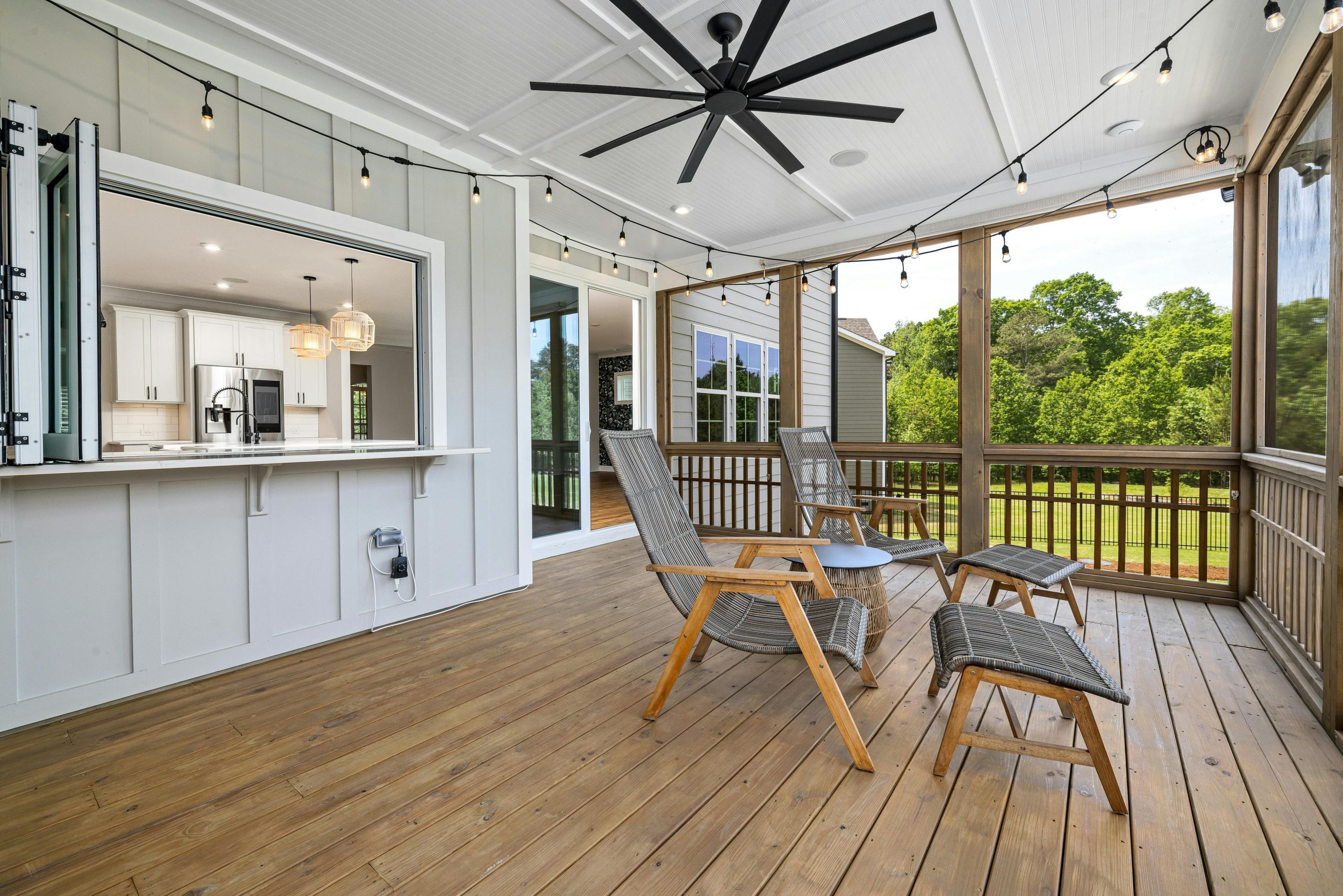 Inviting porch with modern design featuring wooden chairs, ceiling fan, and scenic view.