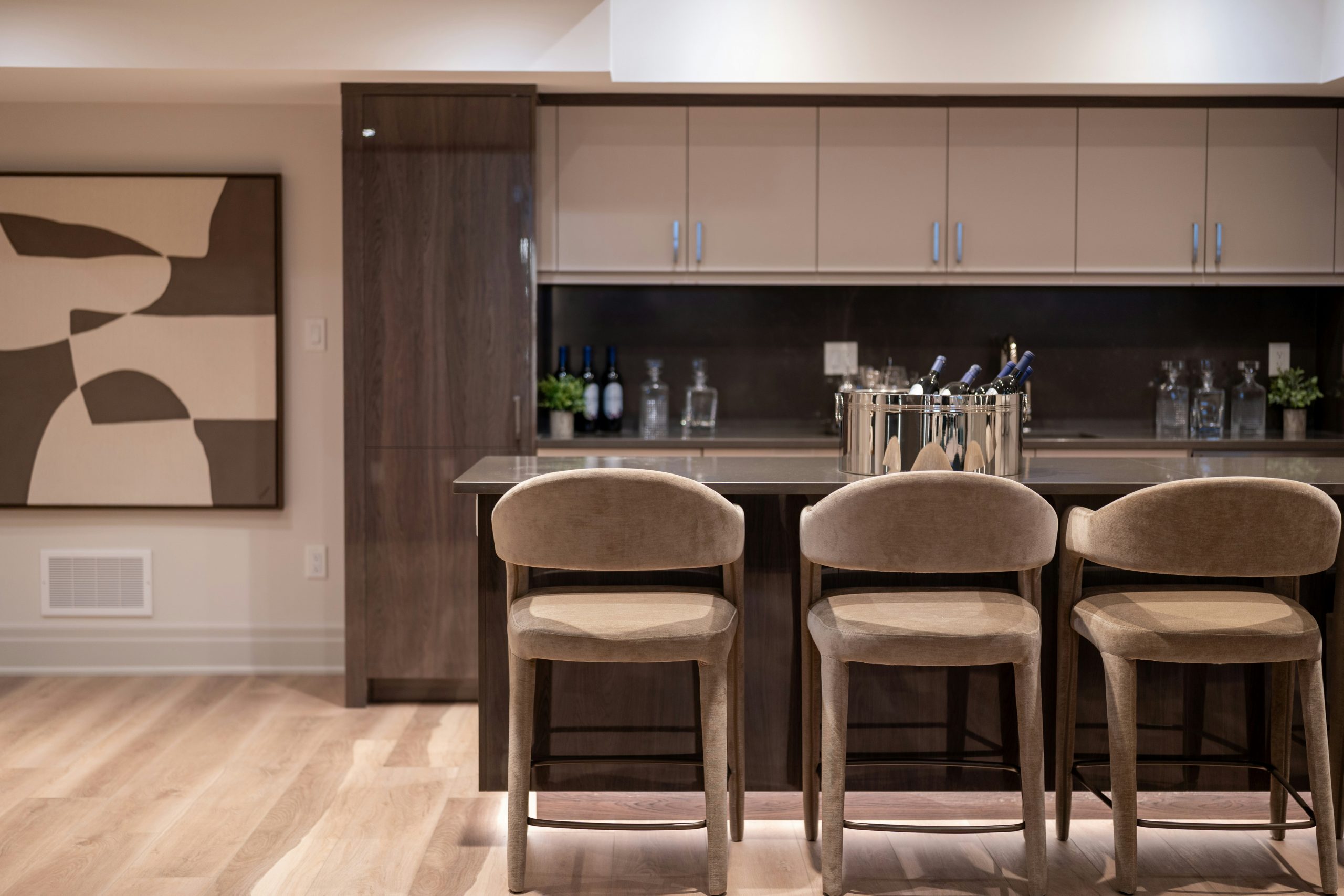 Modern bar area with three stools and wine bottles