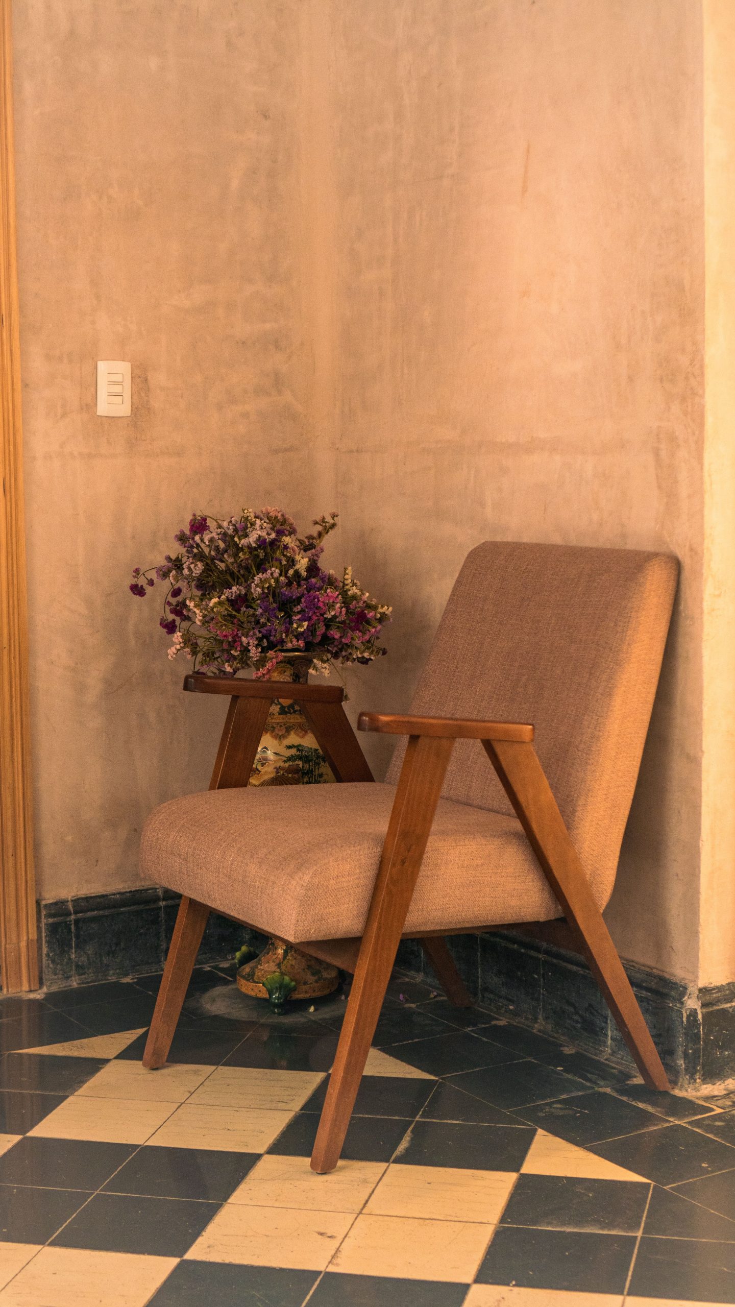 Peaceful corner with vintage armchair and floral arrangement in a room.