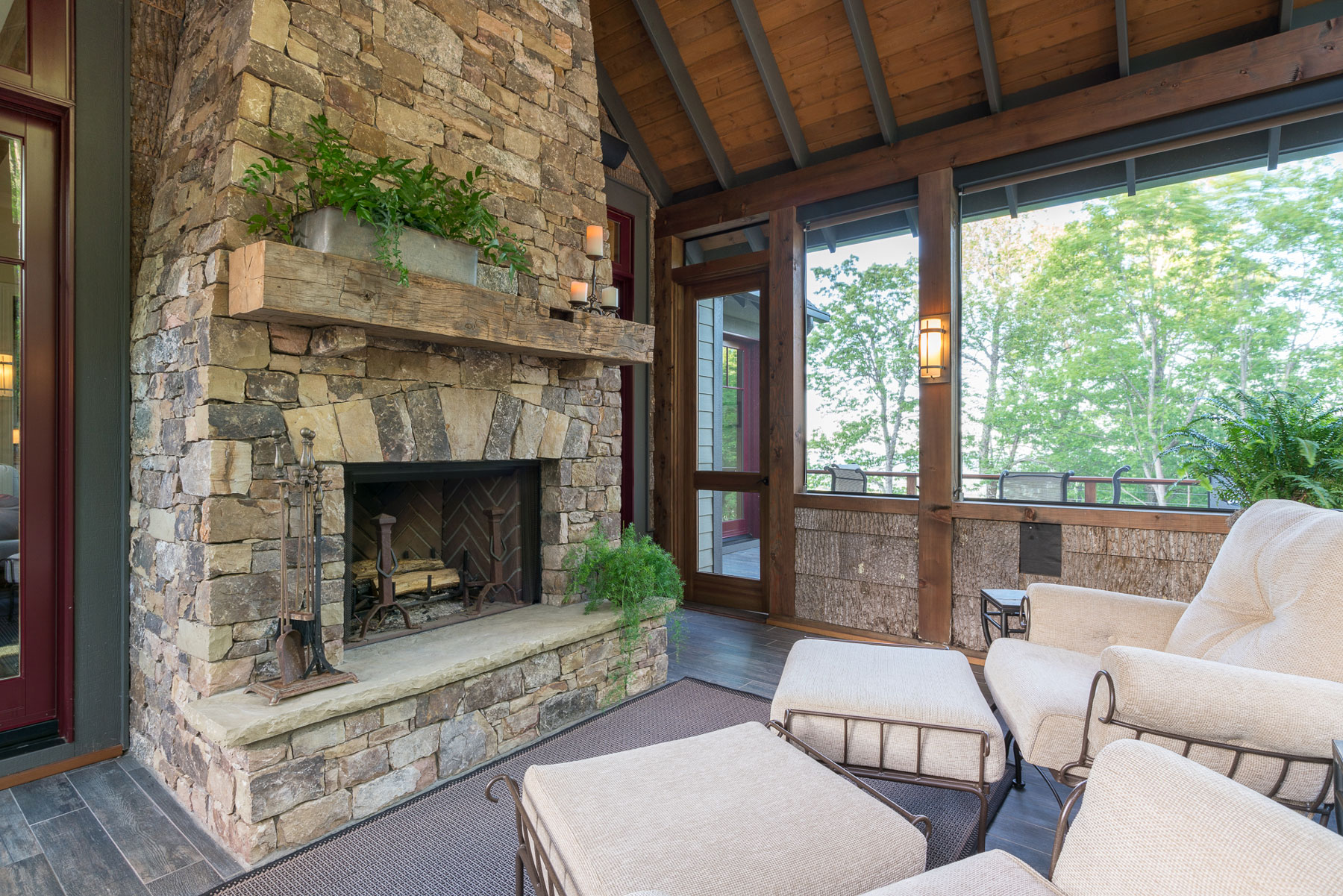 Screened porch with stacked stone fireplace and birch bar walls | ACM Design Architecture & Interiors