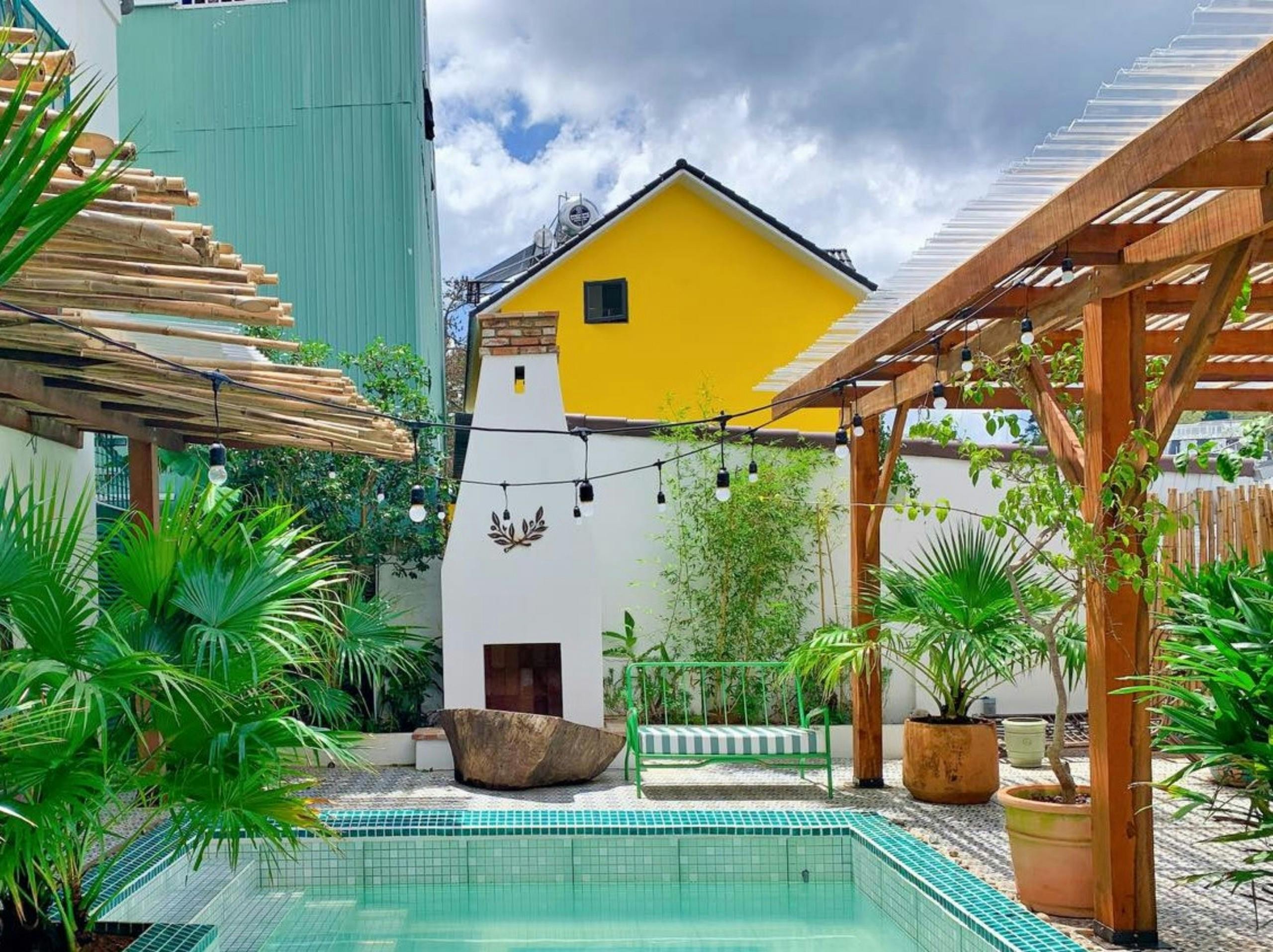 Serene outdoor pool area in Đà Lạt with vibrant plants and rustic architecture.