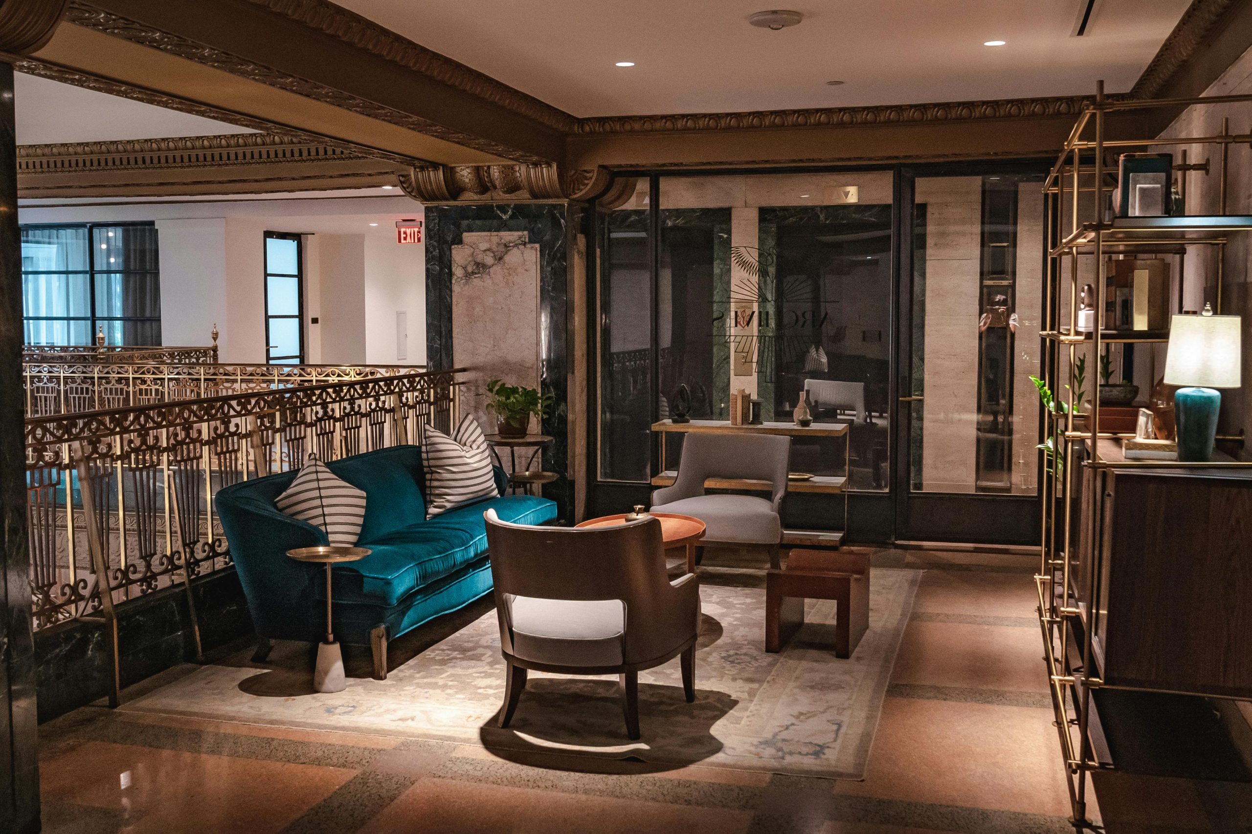 Sophisticated hotel lounge featuring velvet couch, armchairs, and elegant decor in cozy lighting.