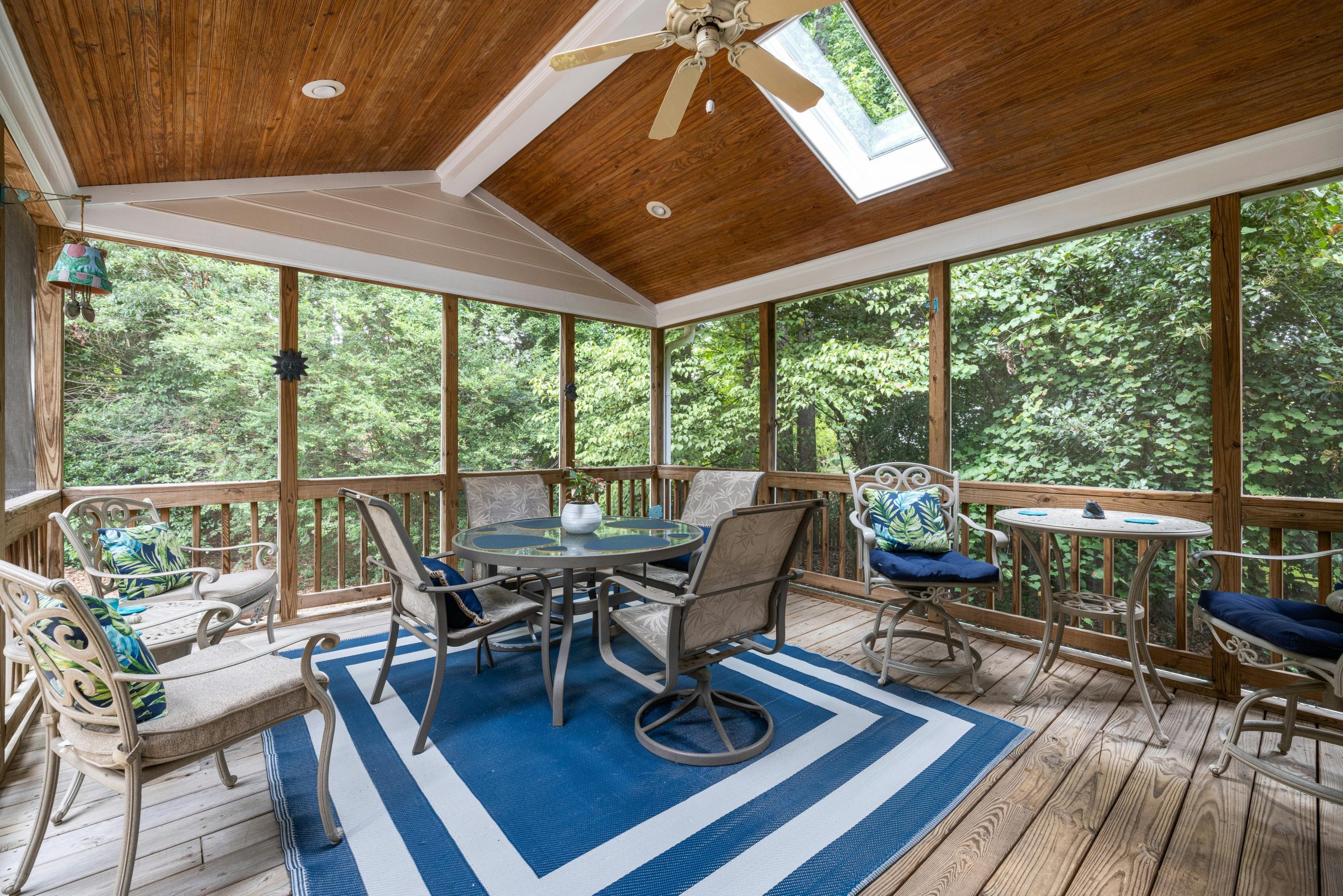 Spacious indoor terrace with elegant patio furniture and forest view, ideal for relaxation.