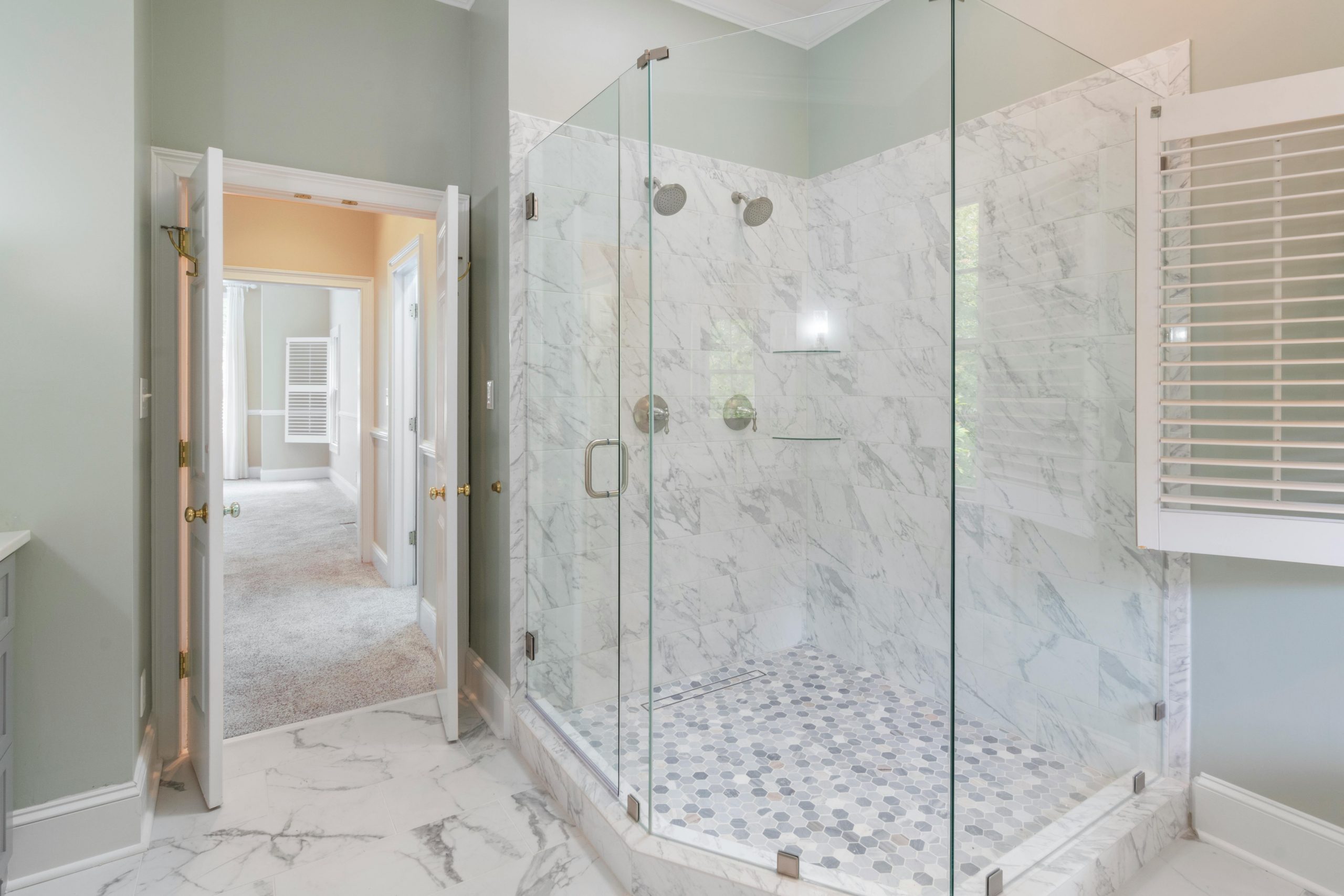 Spacious luxury bathroom featuring a contemporary marble shower with glass doors and elegant interior design.
