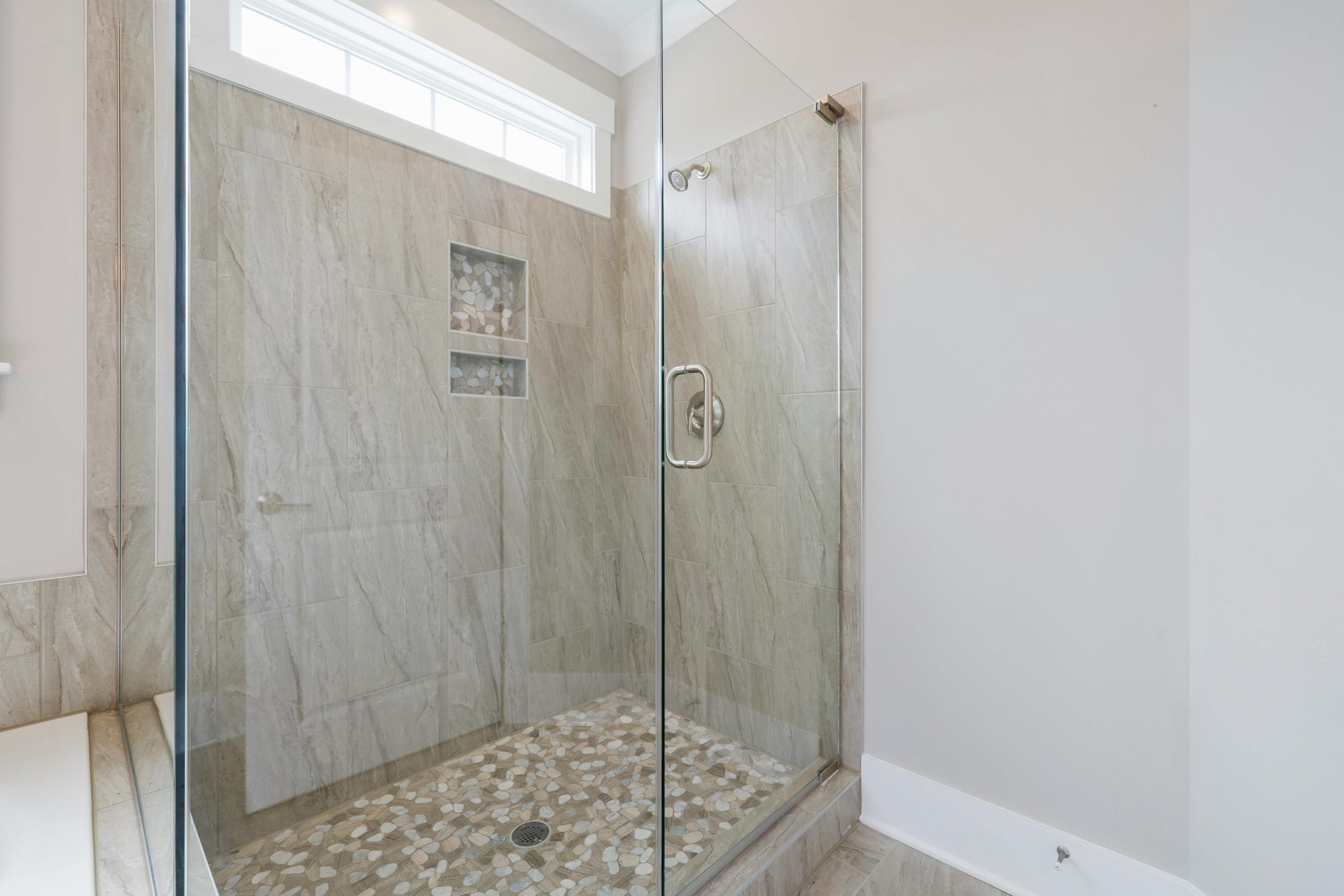 Spacious luxury bathroom featuring a contemporary marble shower with glass doors, combining elegance and modern design.