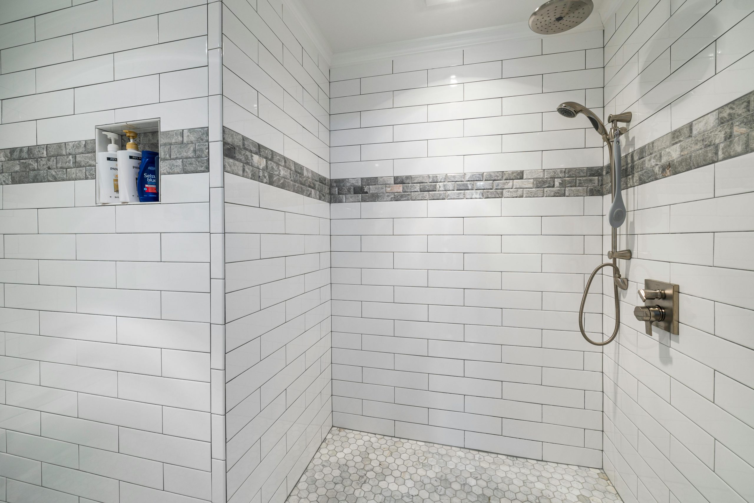 Spacious modern bathroom with white tiles and sleek shower design.