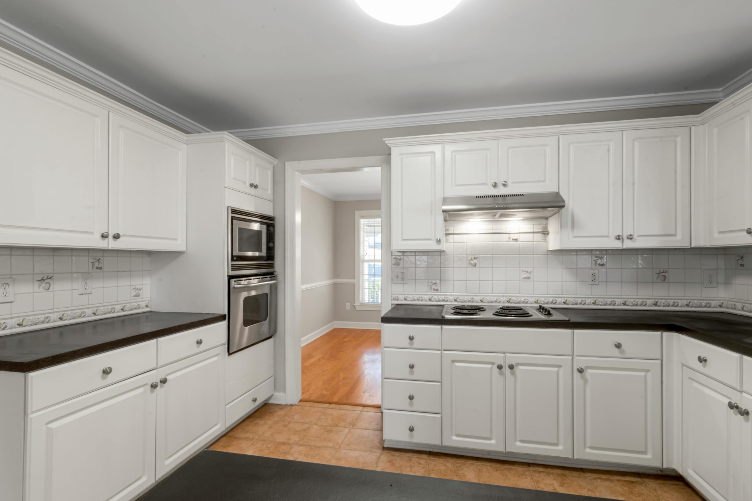 Spacious white kitchen featuring stainless steel appliances and dark countertops.