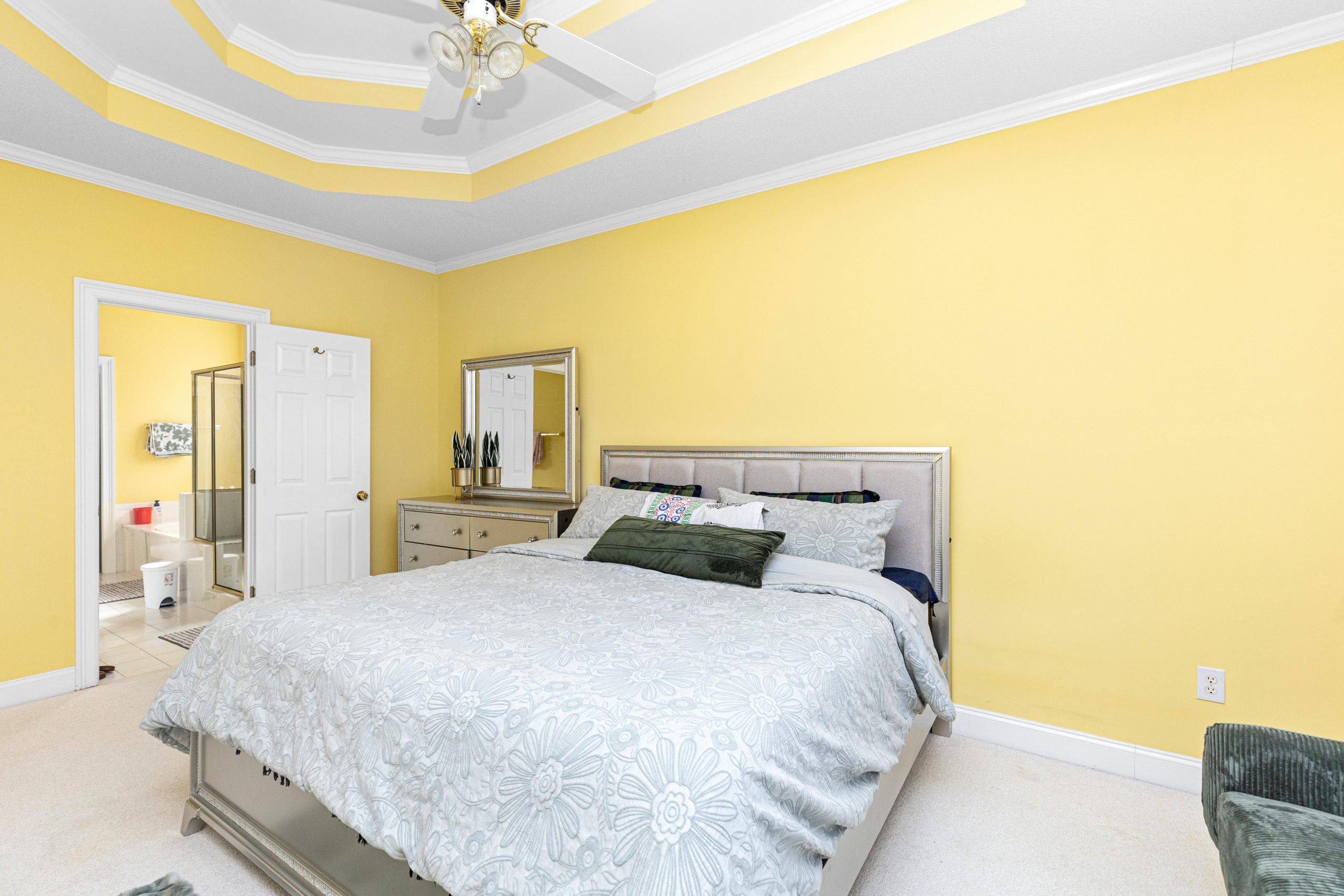 Stylish bedroom interior with yellow walls, white ceiling fan, and queen bed.