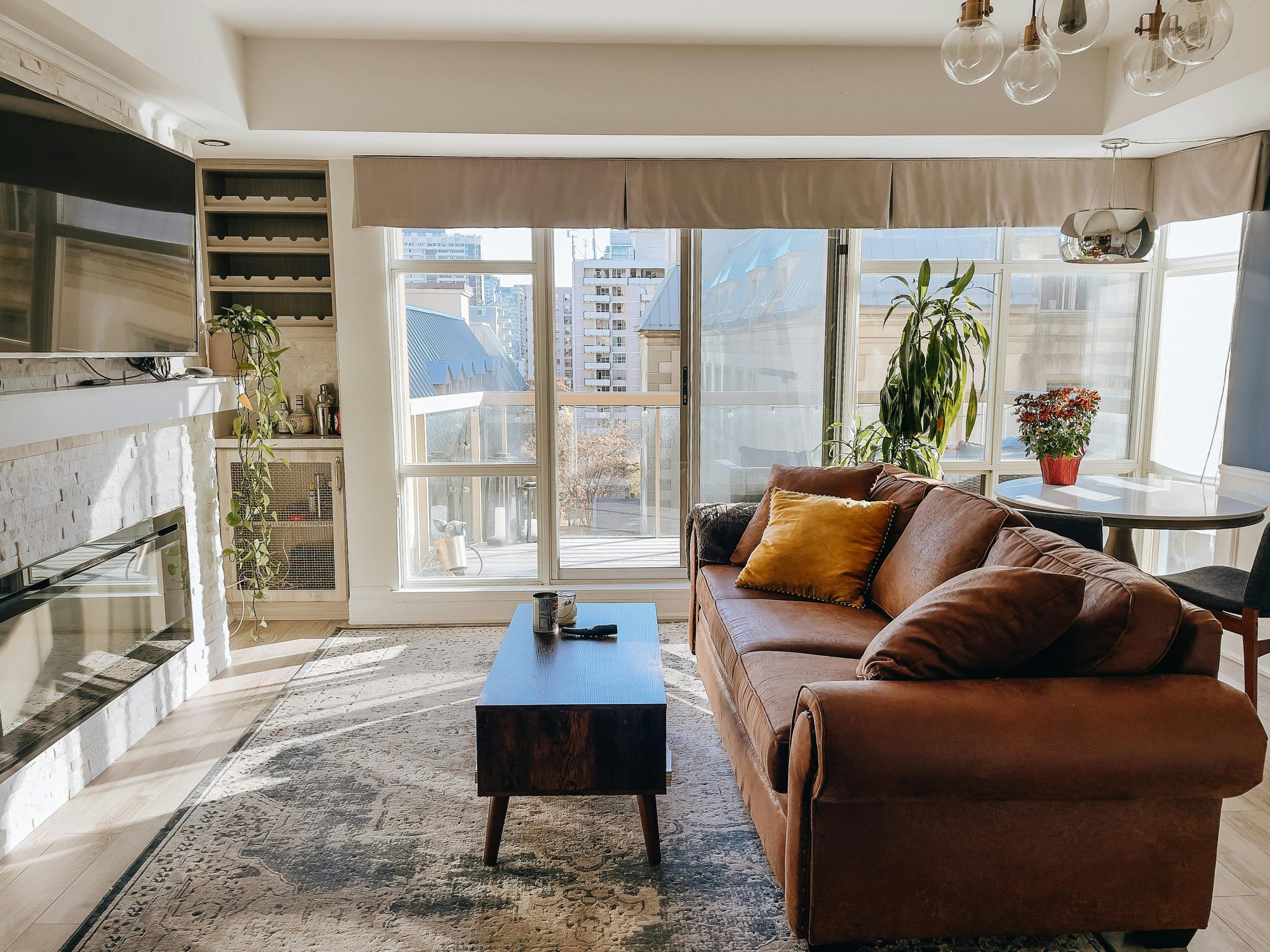Stylish living room with brown sofa and large windows showcasing a cityscape.