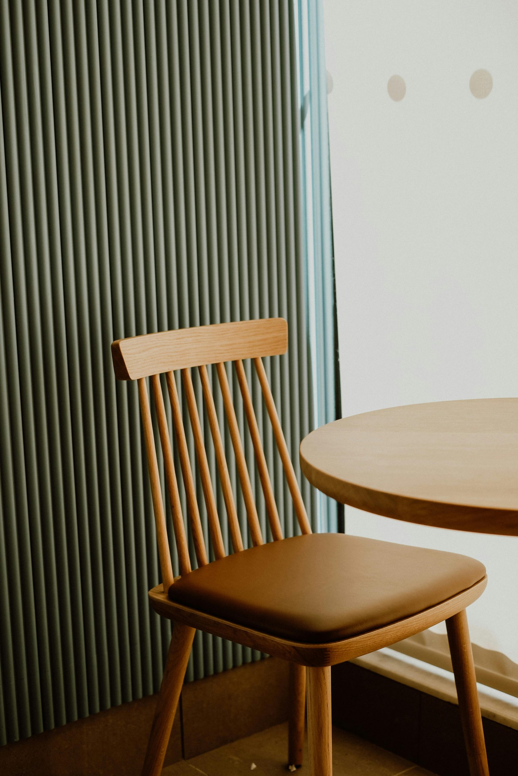 Stylish wooden dining chair and table set in sunlit room with modern decor.