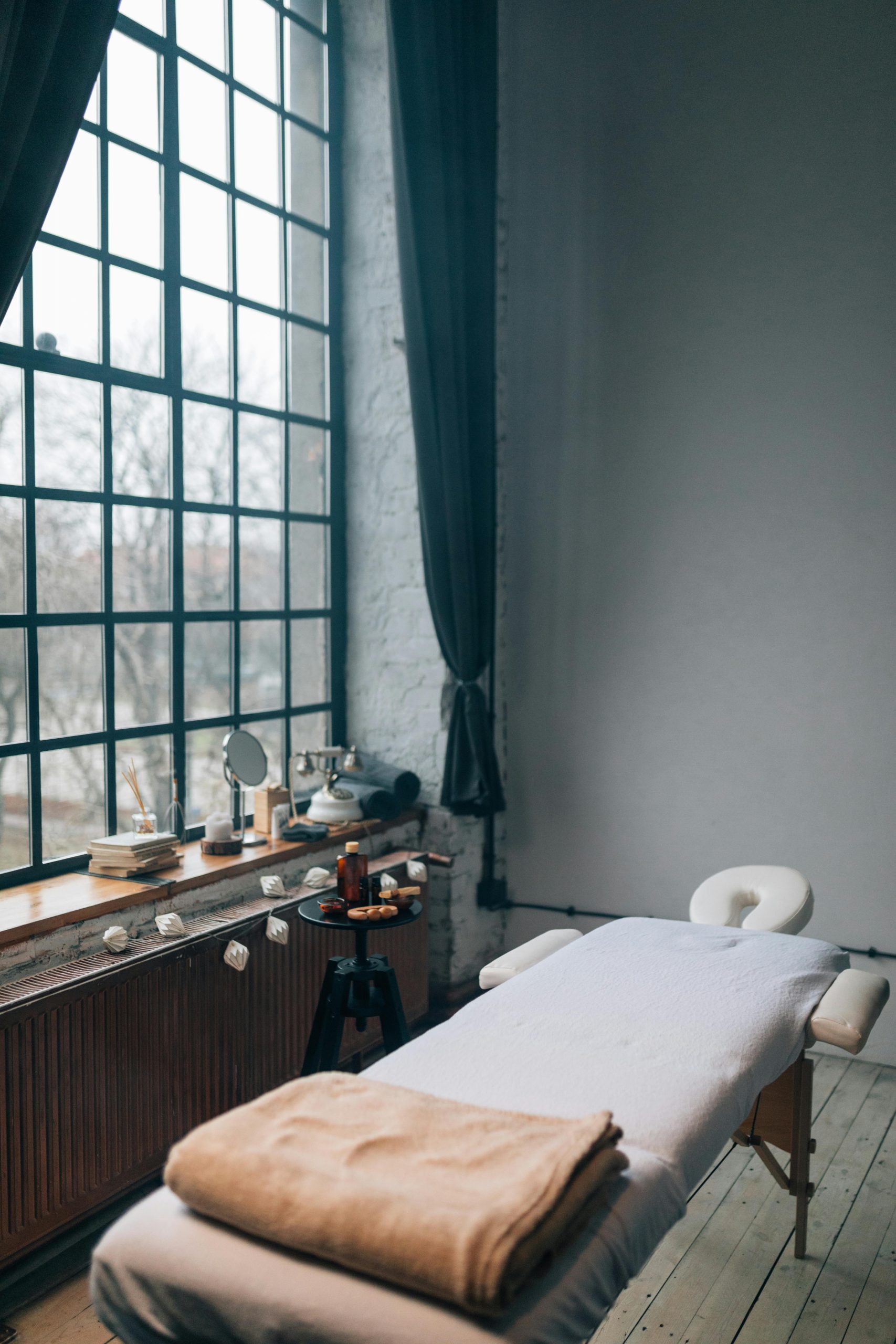 Tranquil massage room setup with natural light from large windows, perfect for relaxation.