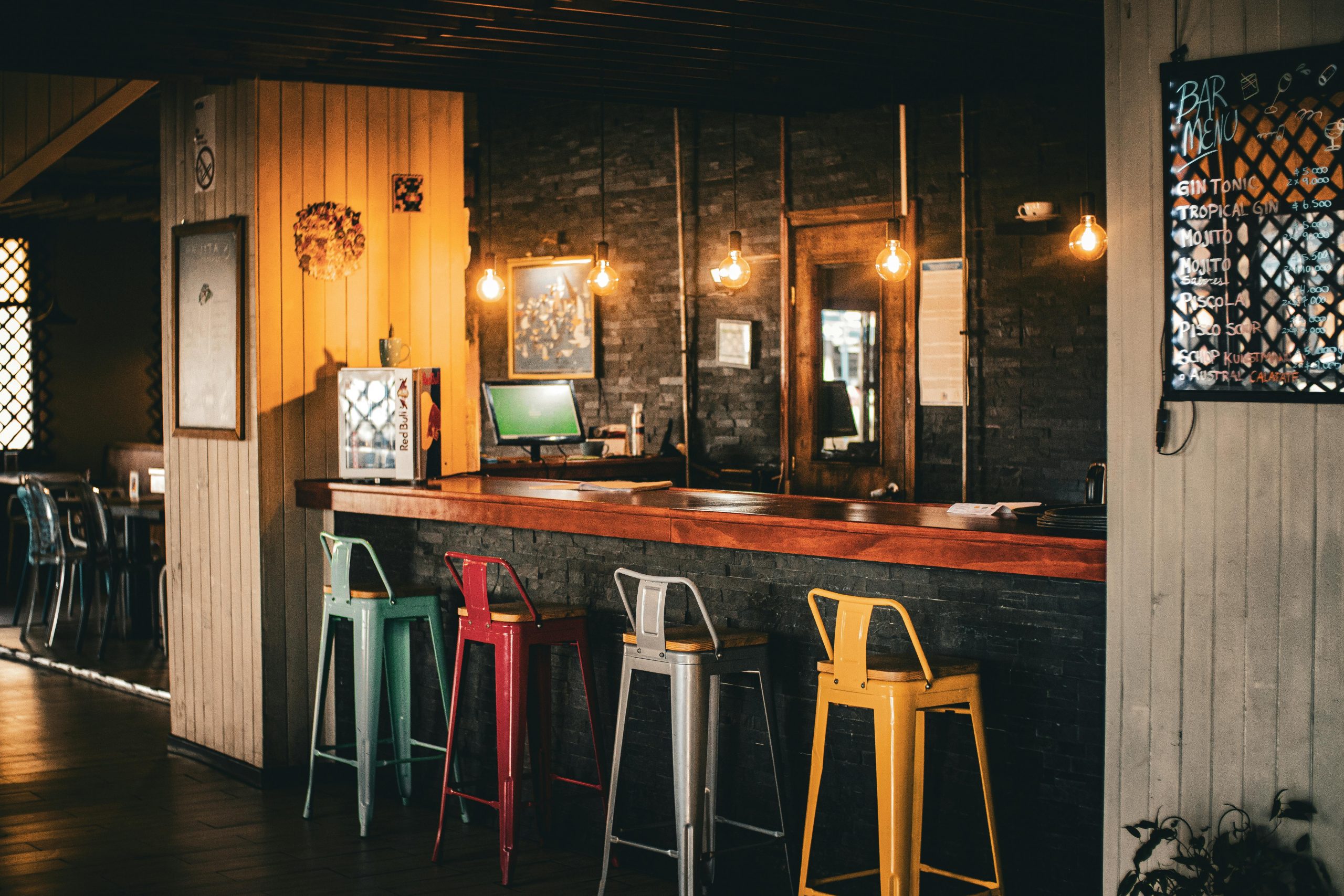 Warm and inviting rustic bar with colorful stools and ambient lighting, perfect for a relaxed evening.