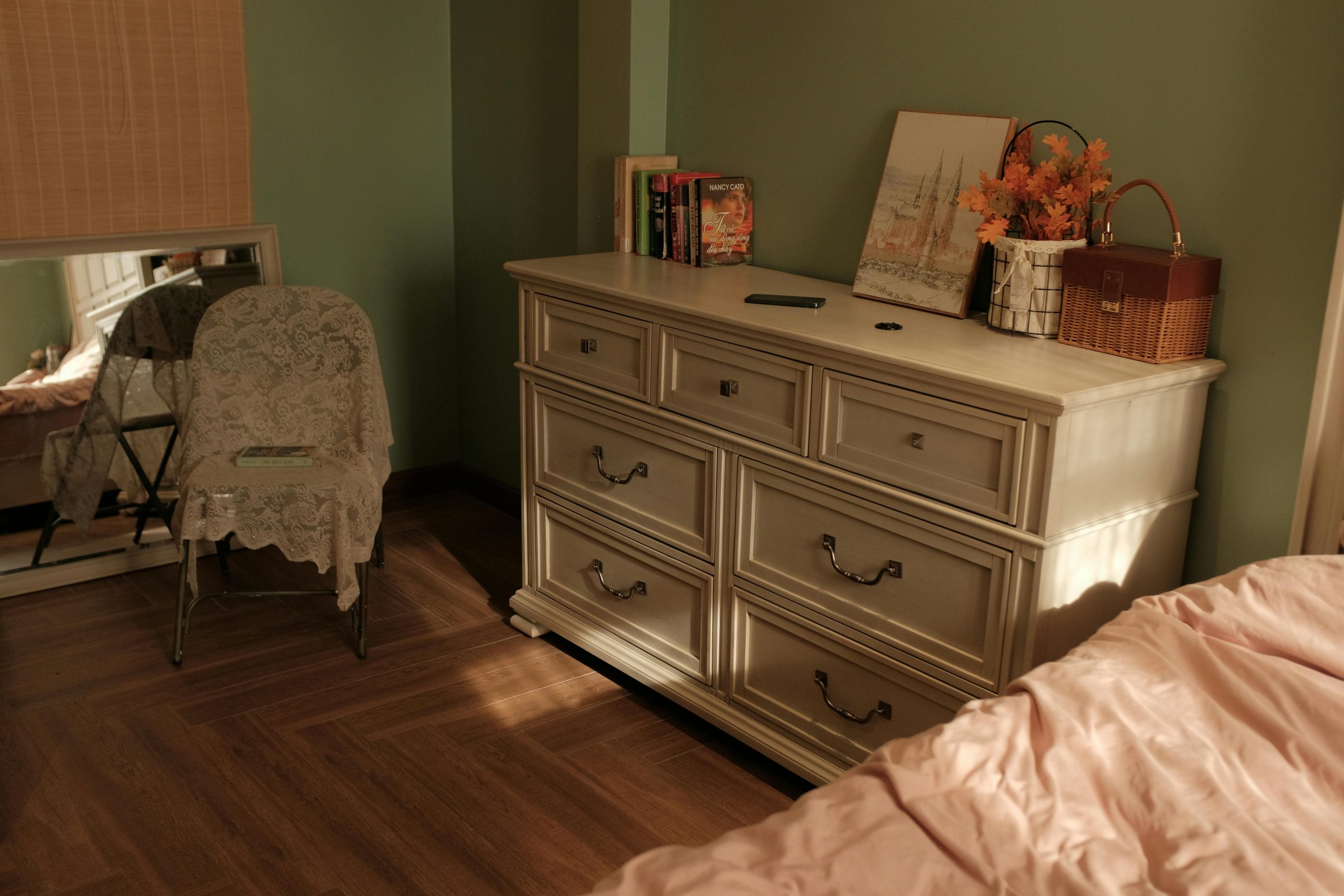 Warm-toned bedroom showcasing vintage decor with a dresser and lace-covered chair.