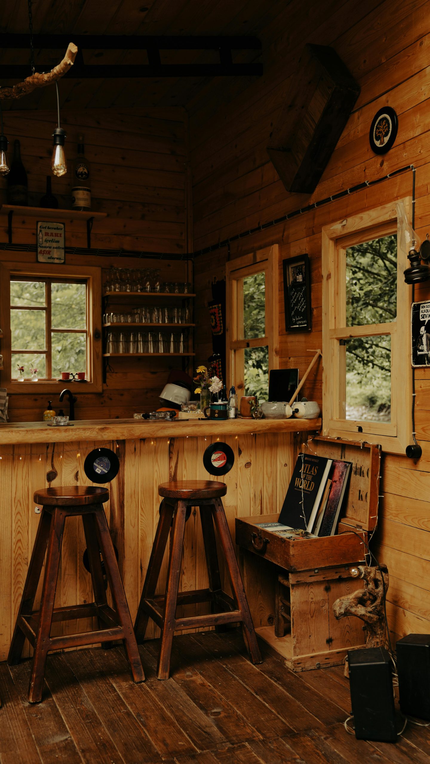 Warm wooden bar interior featuring stools, windows, and rustic decor for a cozy atmosphere.