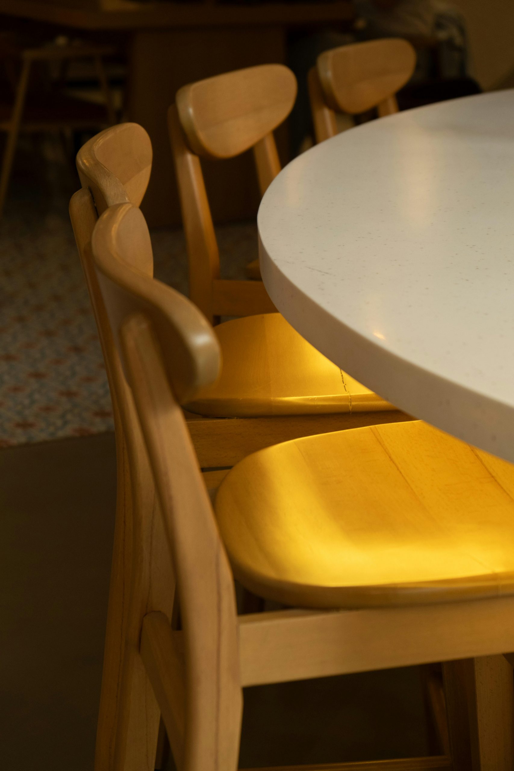 Warm wooden chairs surrounding a clean, round table indoors.
