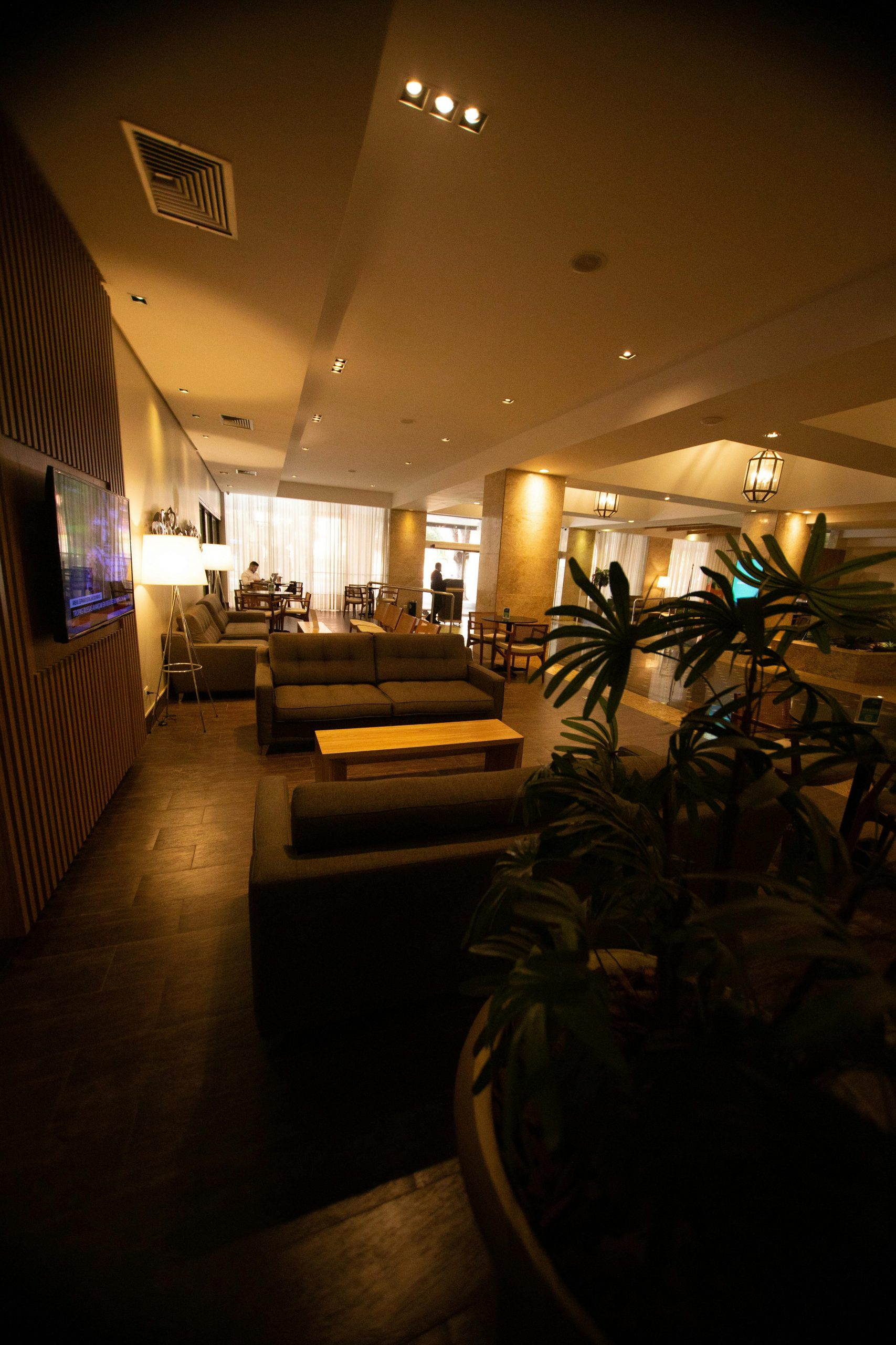 Warmly lit hotel lounge featuring cozy seating, plants, and a modern design.