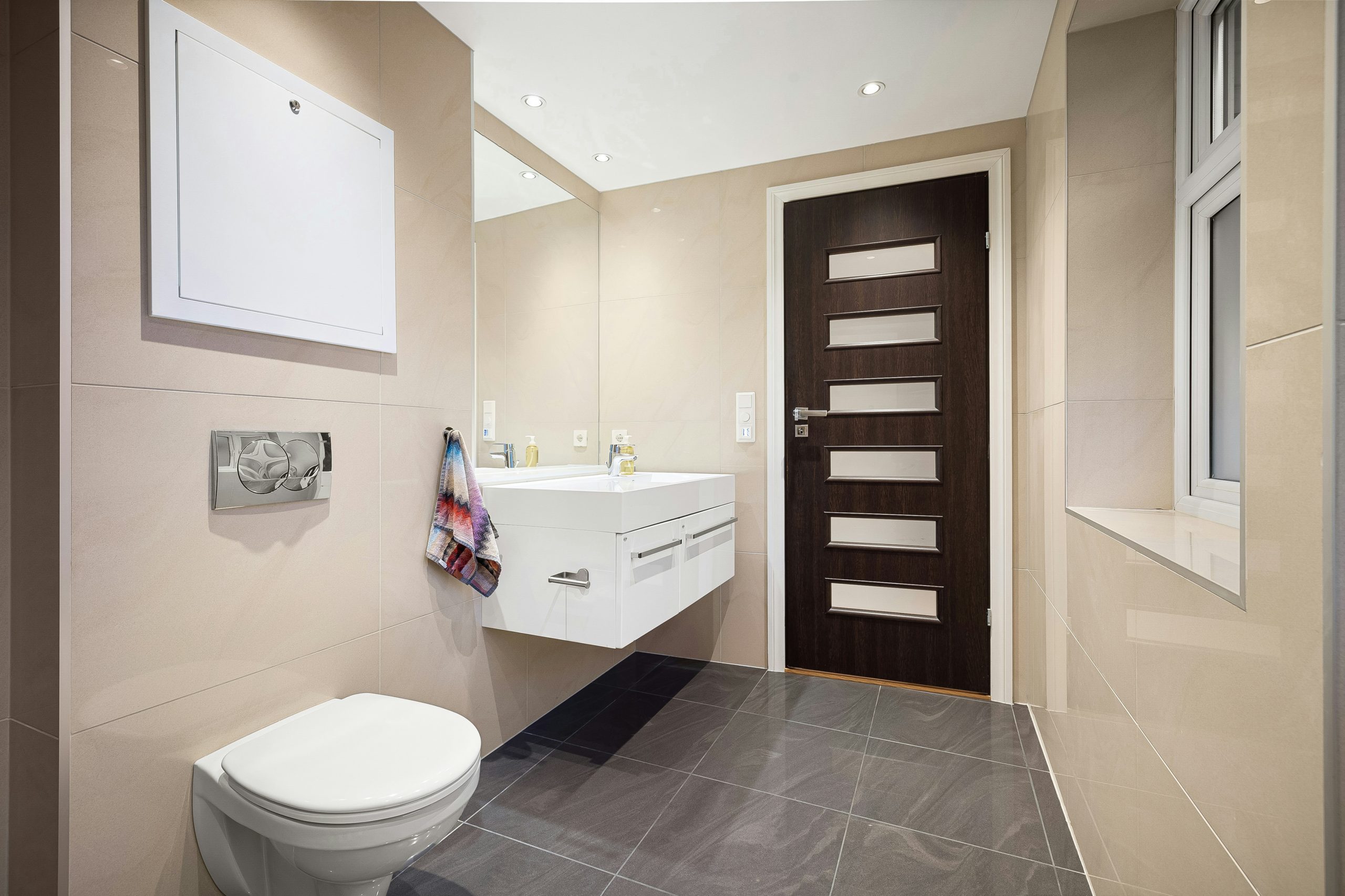 A bathroom with a toilet, sink, and mirror