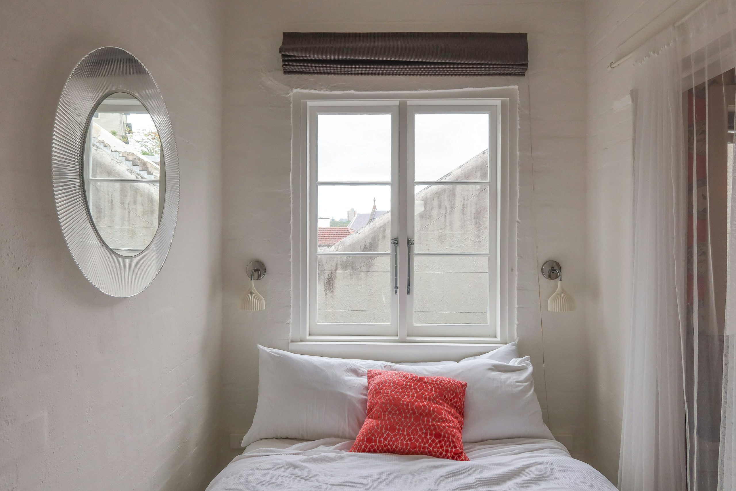 A bedroom with a white bed and a round window
