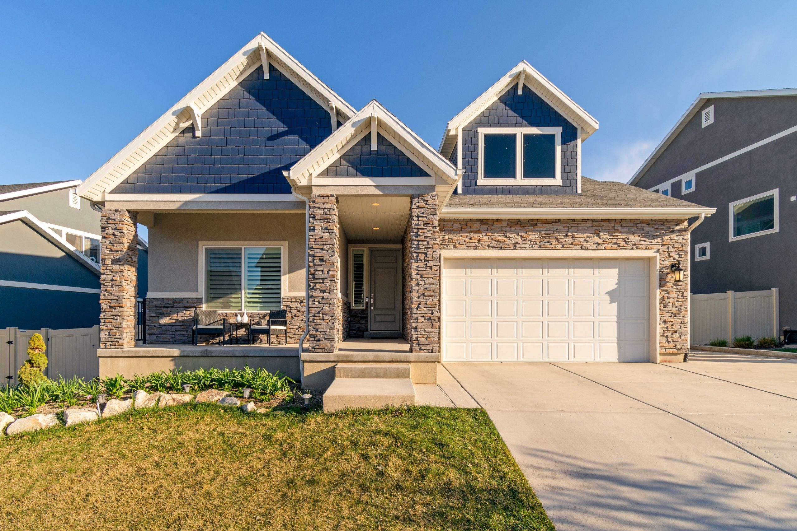 A charming modern suburban home with a stone facade and a neatly maintained lawn.
