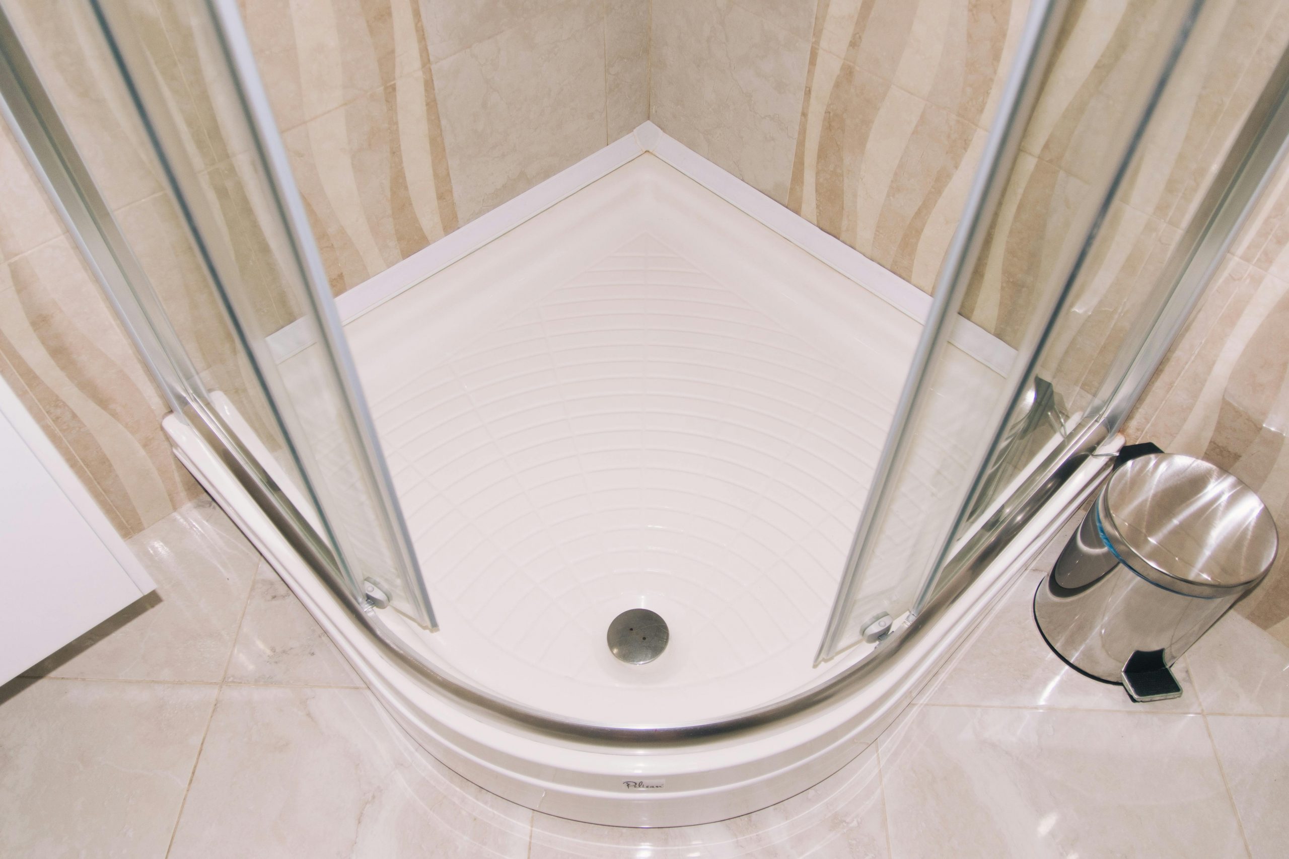 A clean, modern corner shower enclosure with glass doors in a tiled bathroom setting.