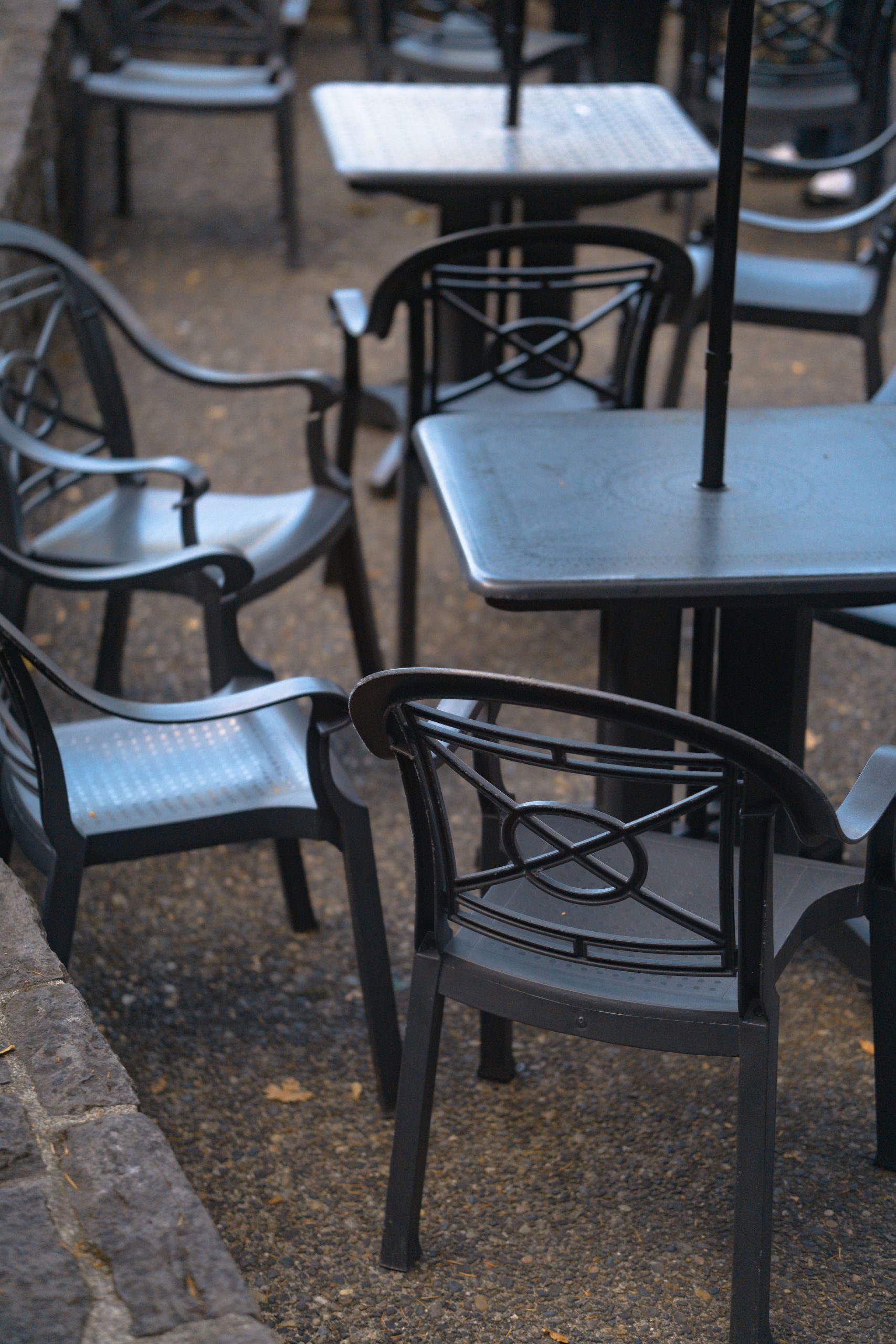 A close-up of metal chairs and tables arranged in a cozy outdoor patio scene.
