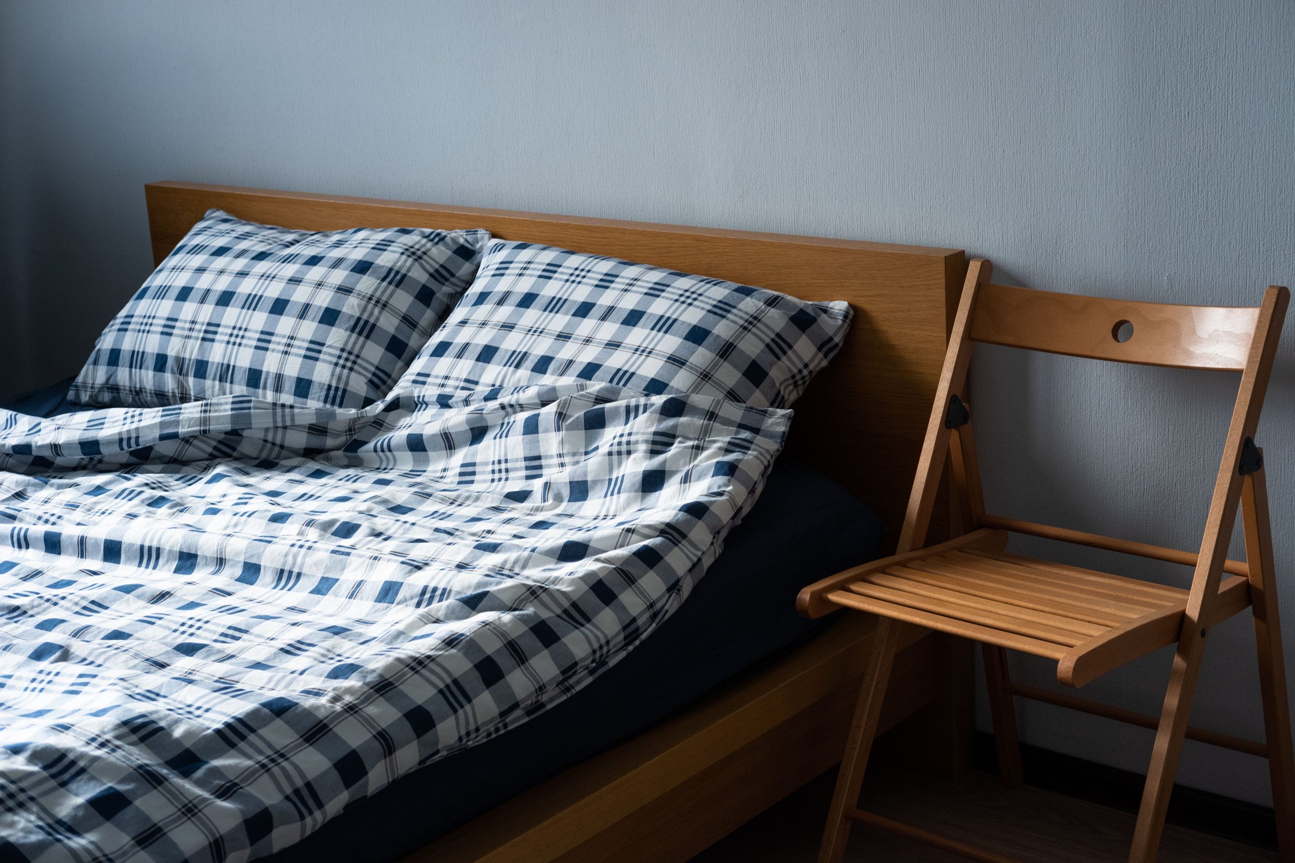 A comfortable bedroom scene featuring plaid linens and wooden furniture.