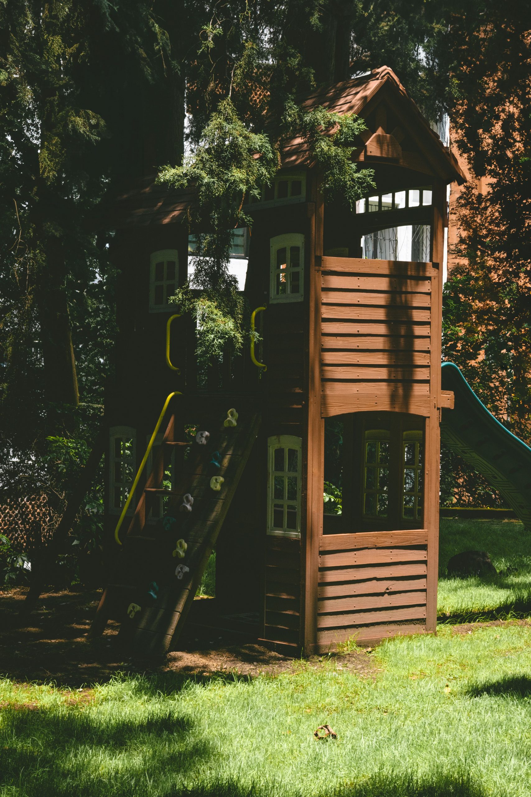 A cozy wooden playhouse nestled in a lush, sunlit forest setting, perfect for outdoor fun.