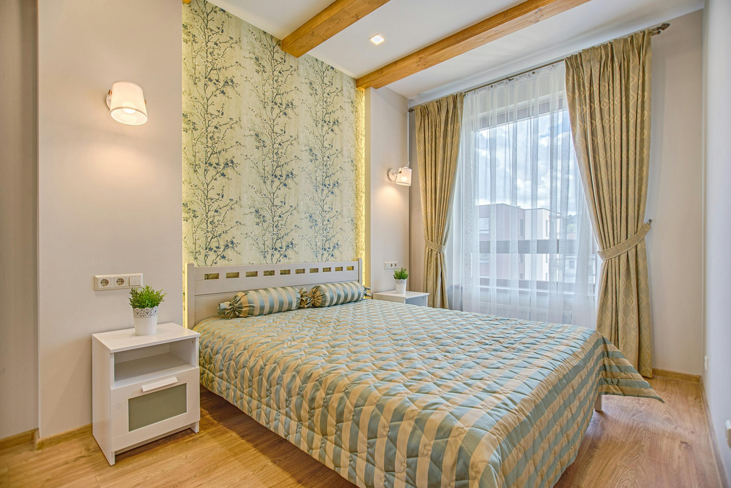 A luxurious and contemporary bedroom design with patterned wallpaper and natural lighting, located in Vilnius, Lithuania.