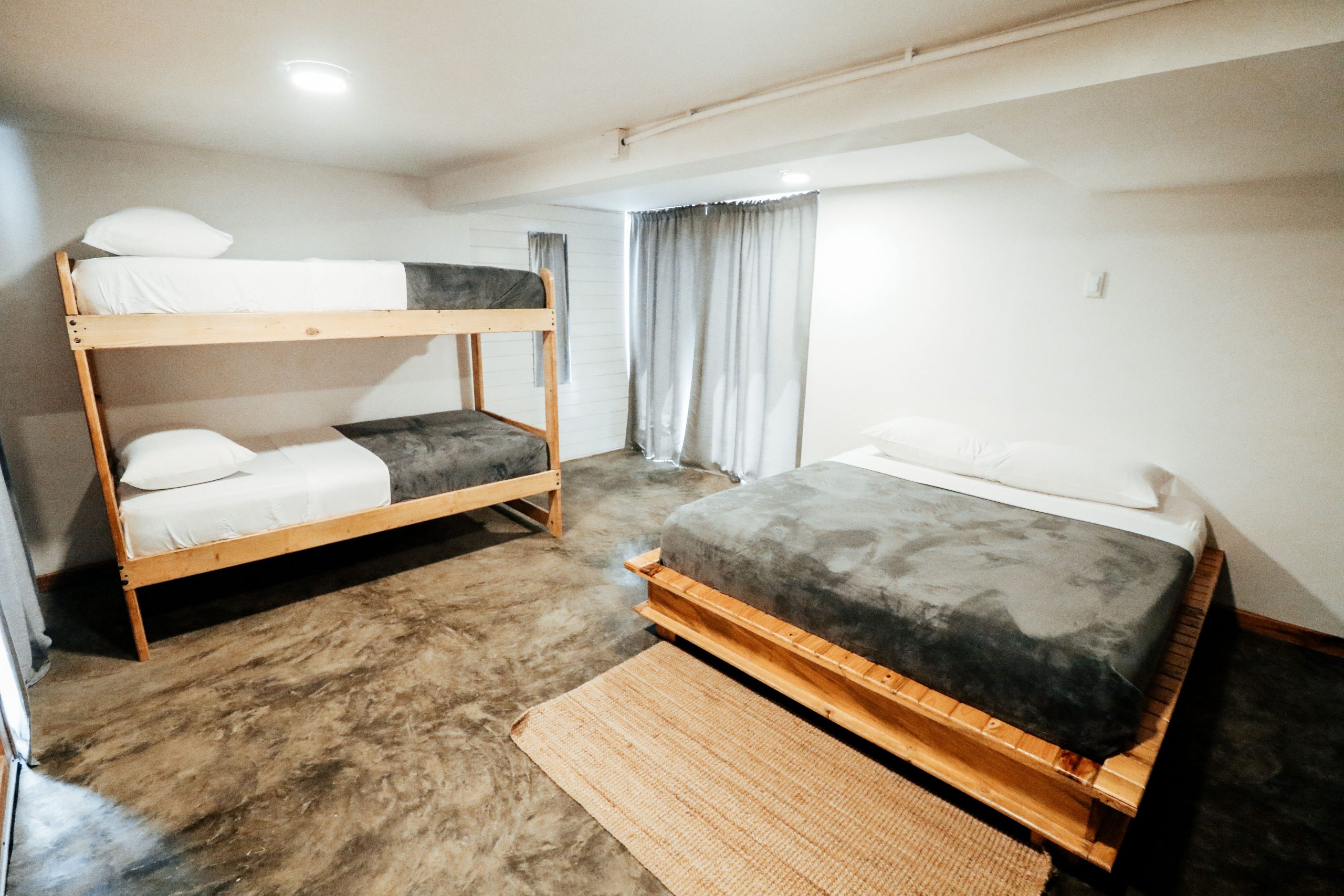 A minimalist bedroom design featuring bunk beds and a double bed with a cozy atmosphere.