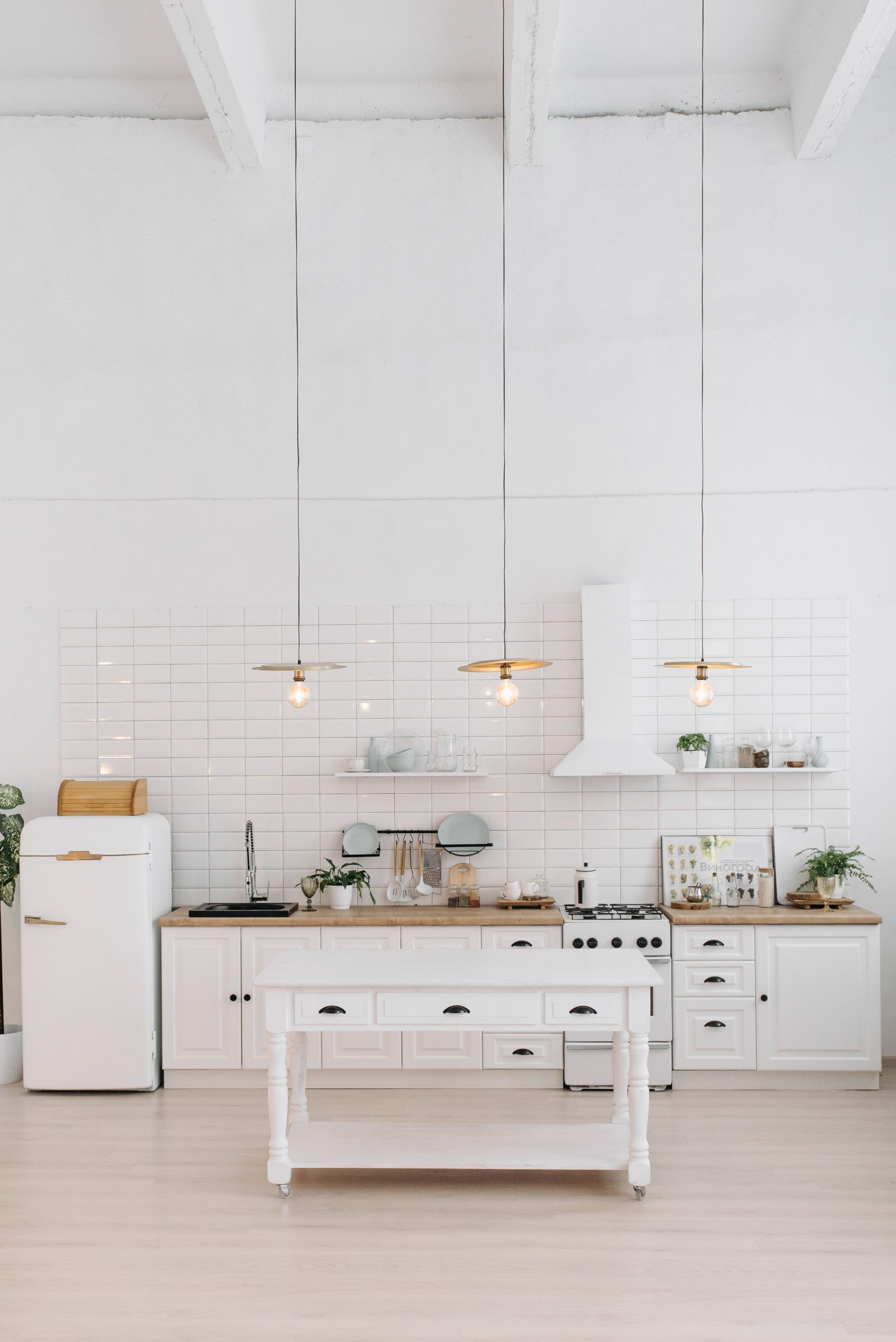 A minimalist white kitchen interior with modern appliances and decor elements.