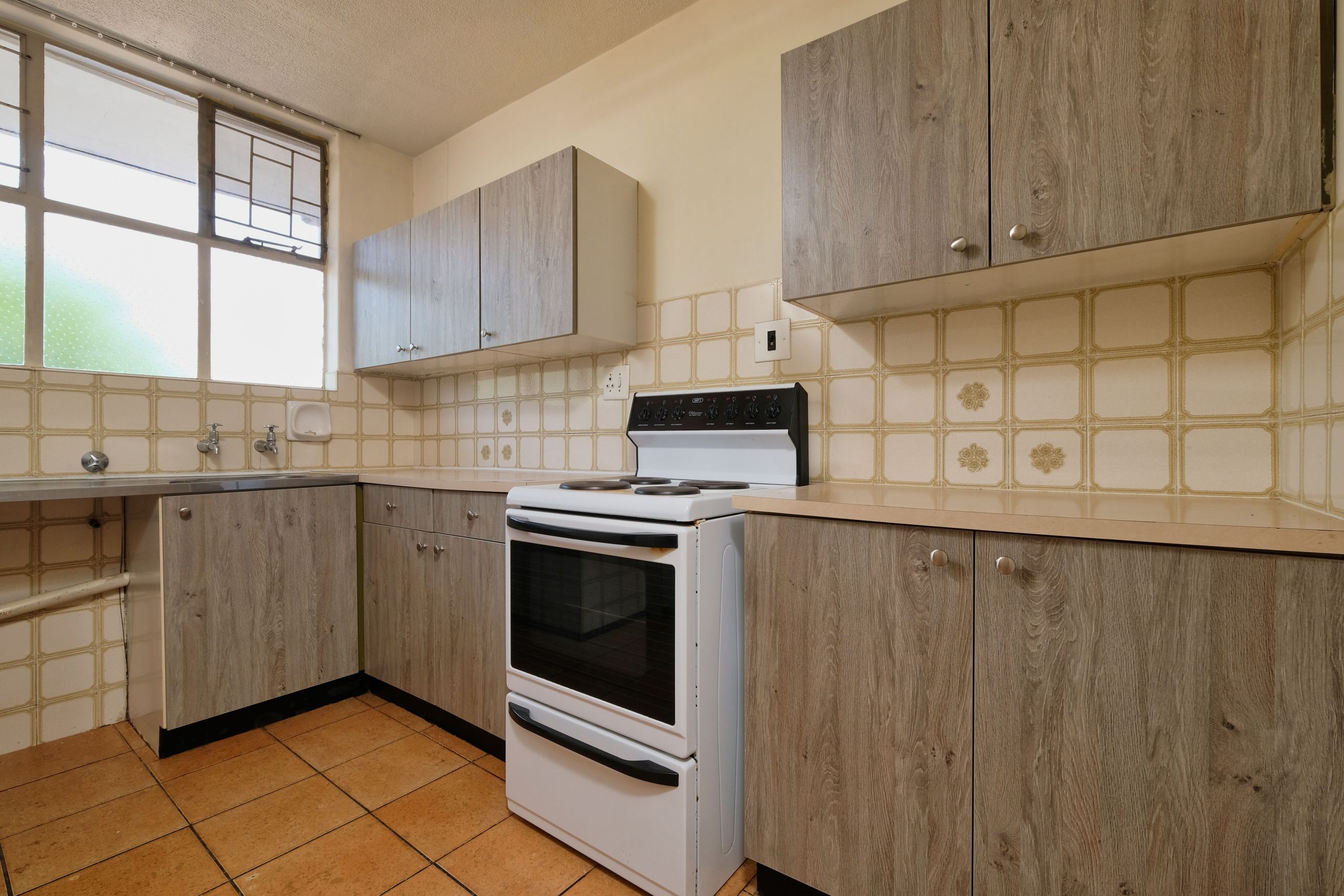 A modern kitchen interior featuring wooden cabinets and a stove in Pretoria, South Africa.