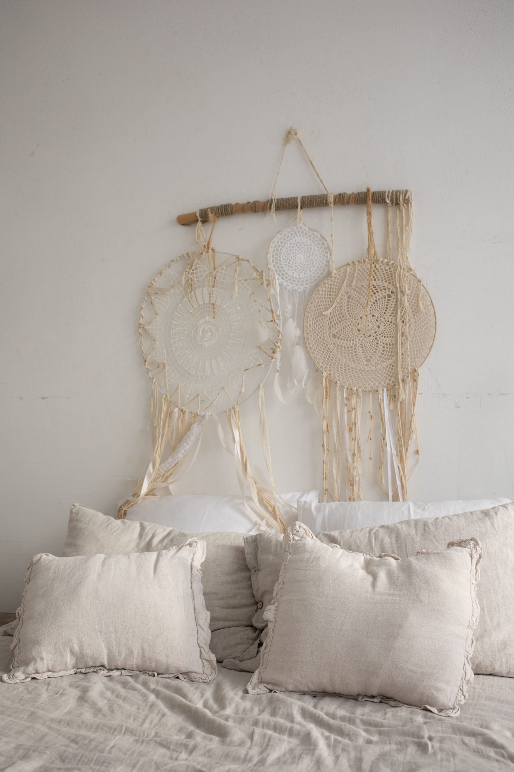 A serene bedroom with bohemian dreamcatchers and pillows over a bed, exuding tranquility.