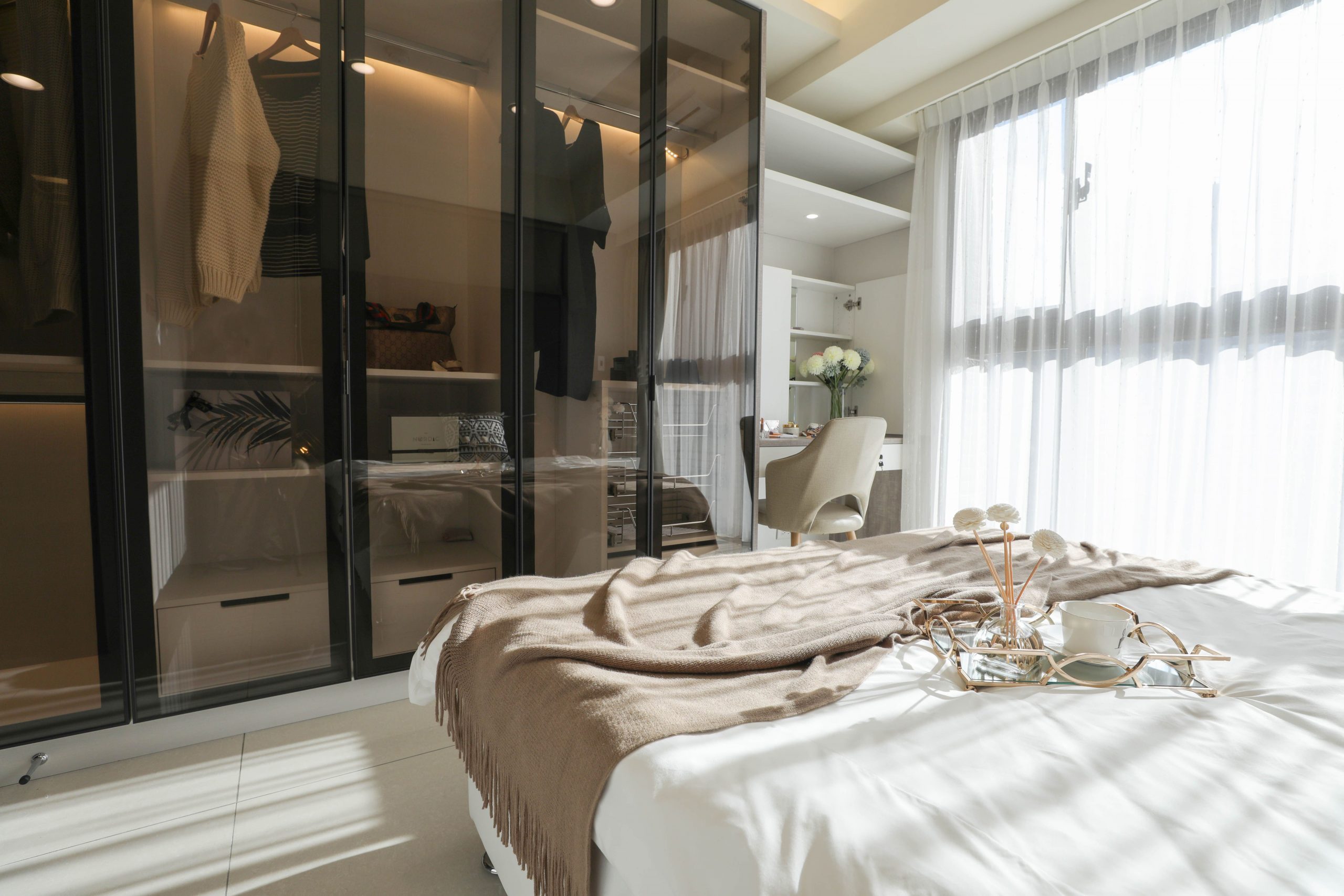 A sleek and stylish bedroom featuring a modern wardrobe and bright sunlight.