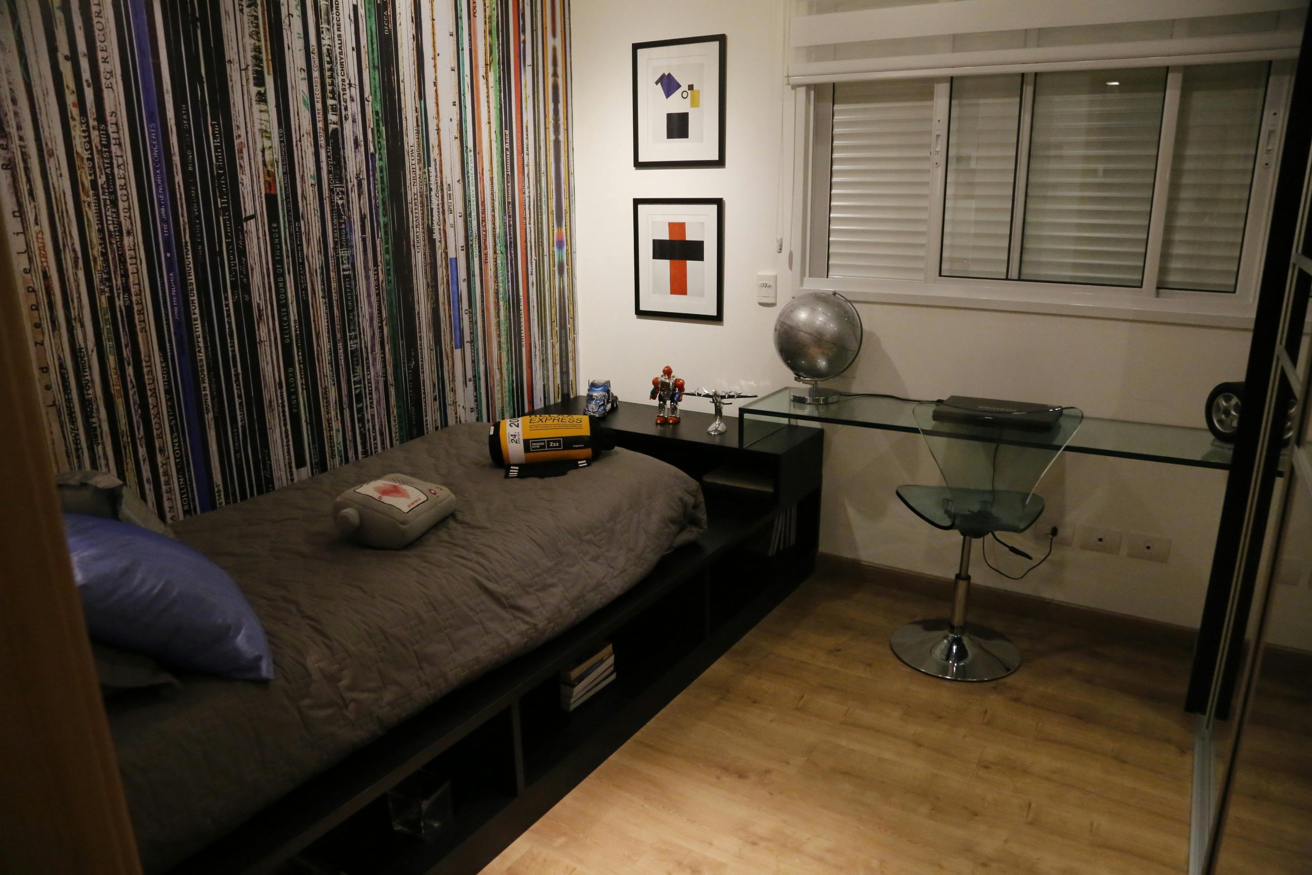 A sleek and stylish bedroom with a bed, glass desk, and modern art decor.