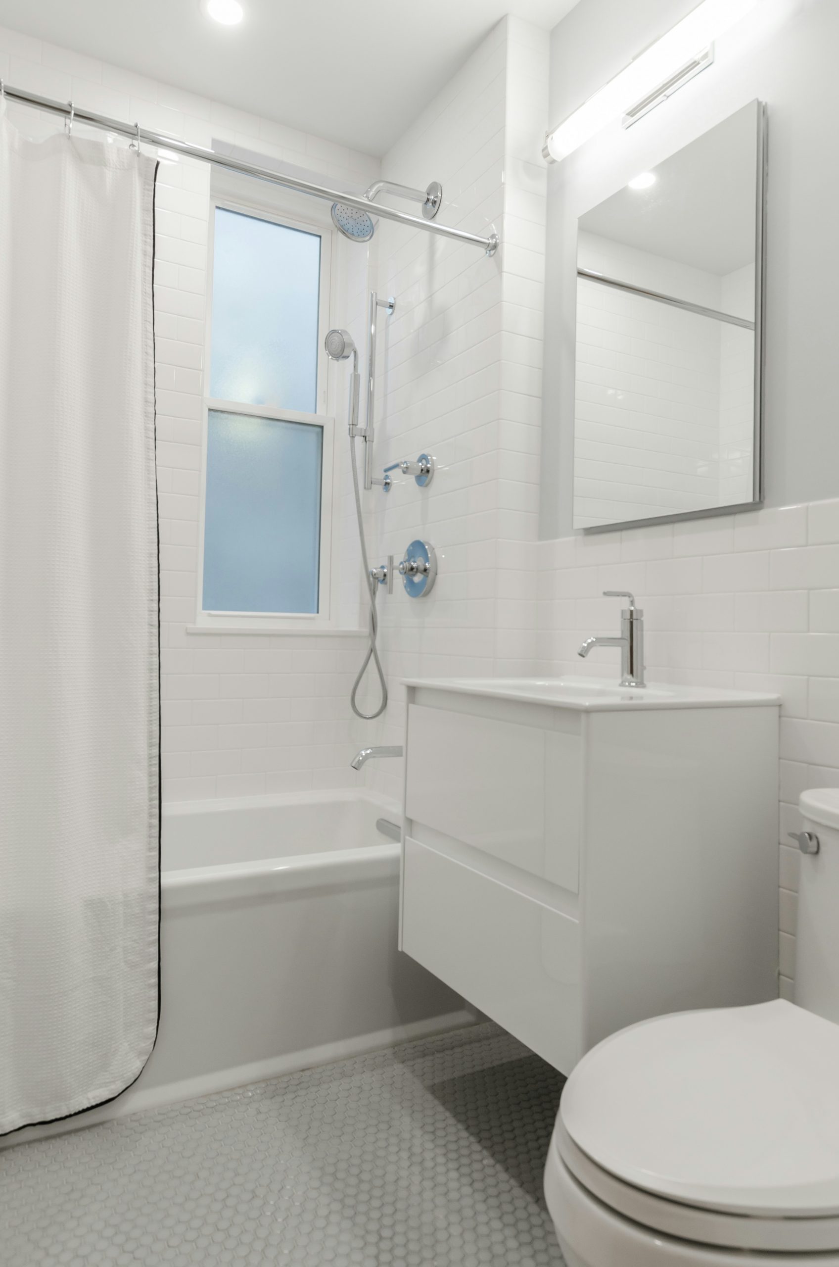 All white bathroom, white bathroom tiles, white subway tiles, chrome faucets, chrome shower head, chrome finishings, bathroom mirror, crystal door knob
