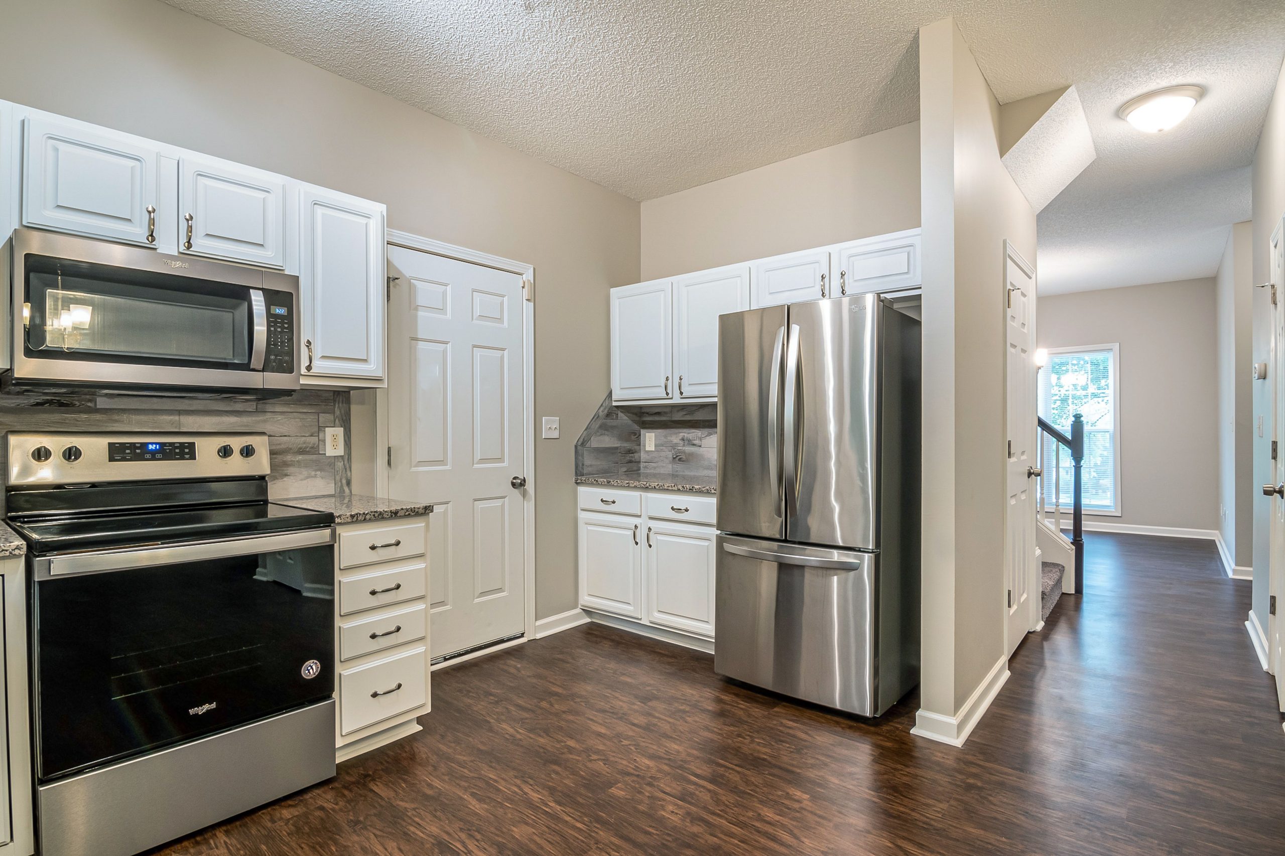 Bright modern kitchen featuring stainless steel appliances and white cabinets.