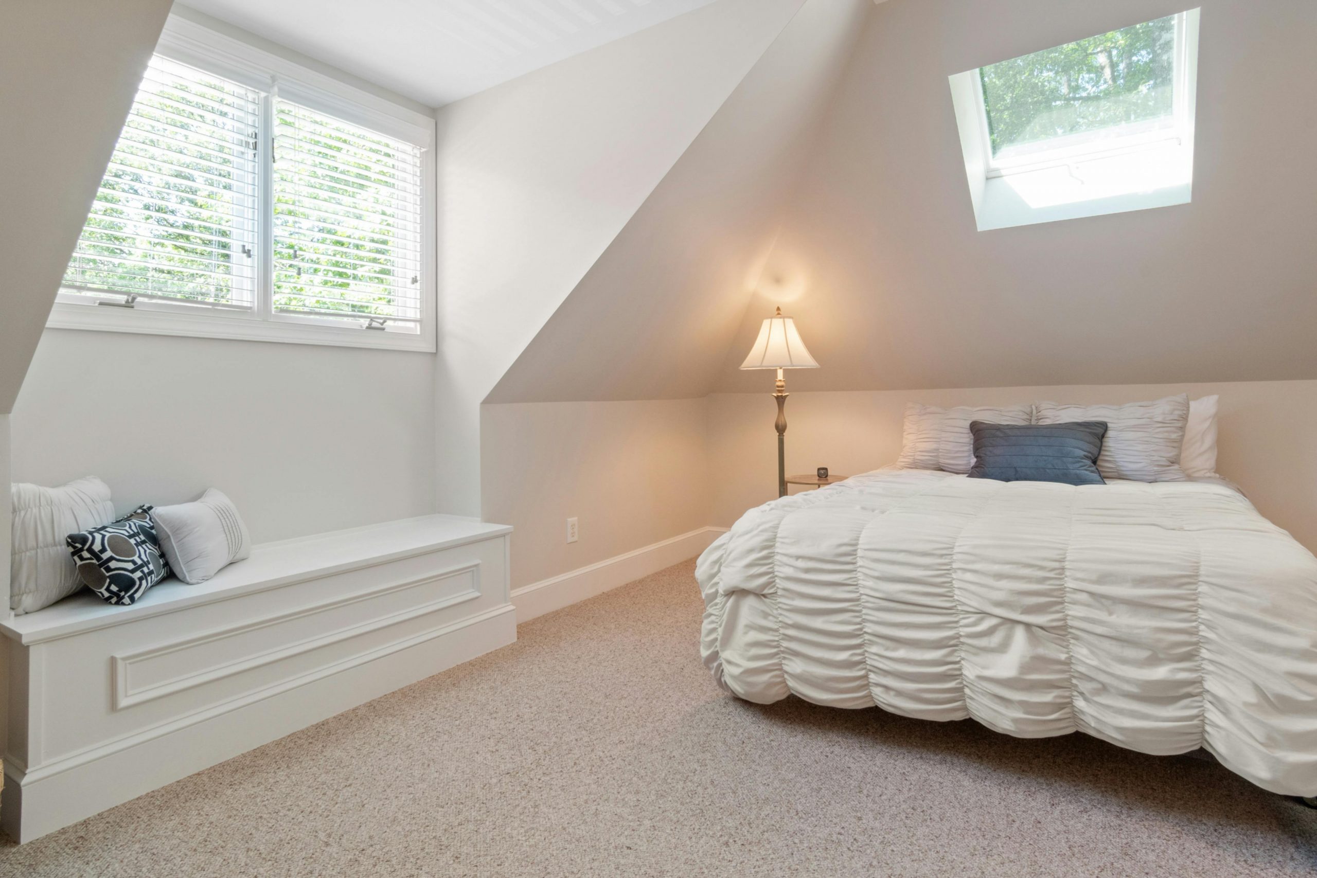 Charming attic bedroom featuring a cozy bed, natural light, and elegant interior design.
