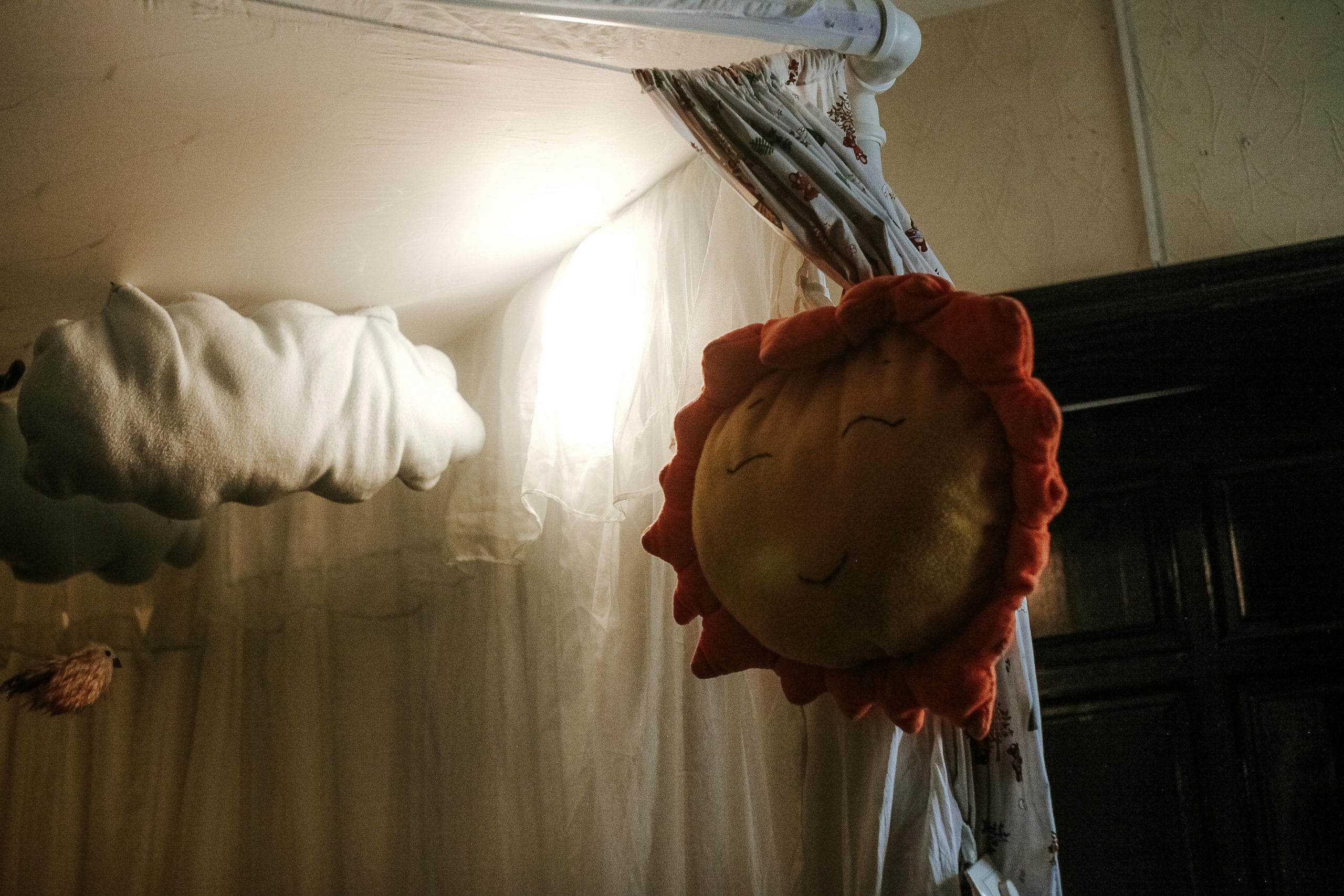 Charming nursery corner with smiling sun and fluffy cloud décor, creating a warm and cozy atmosphere.