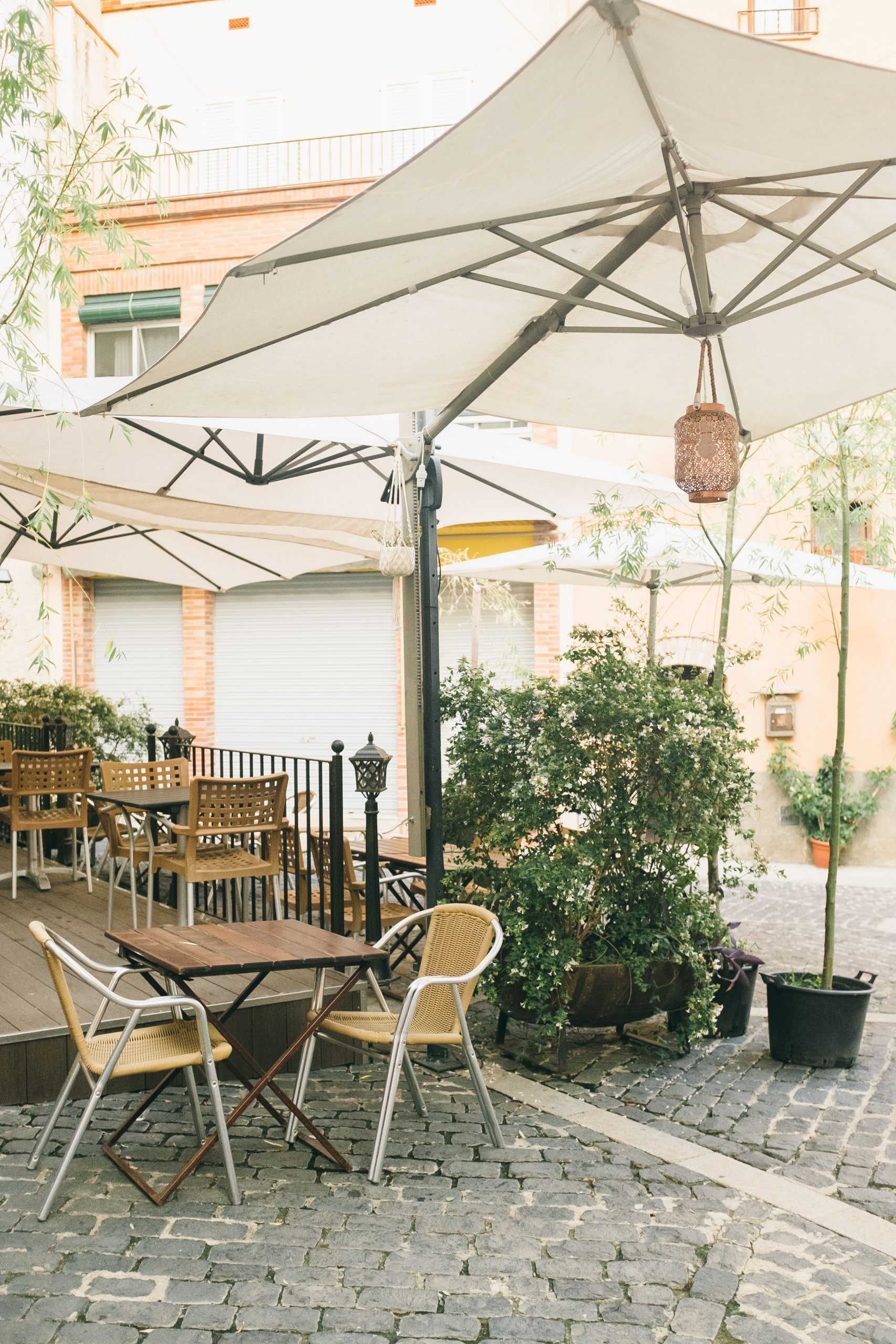 Charming outdoor cafe with seating under large umbrellas on a sunny day.