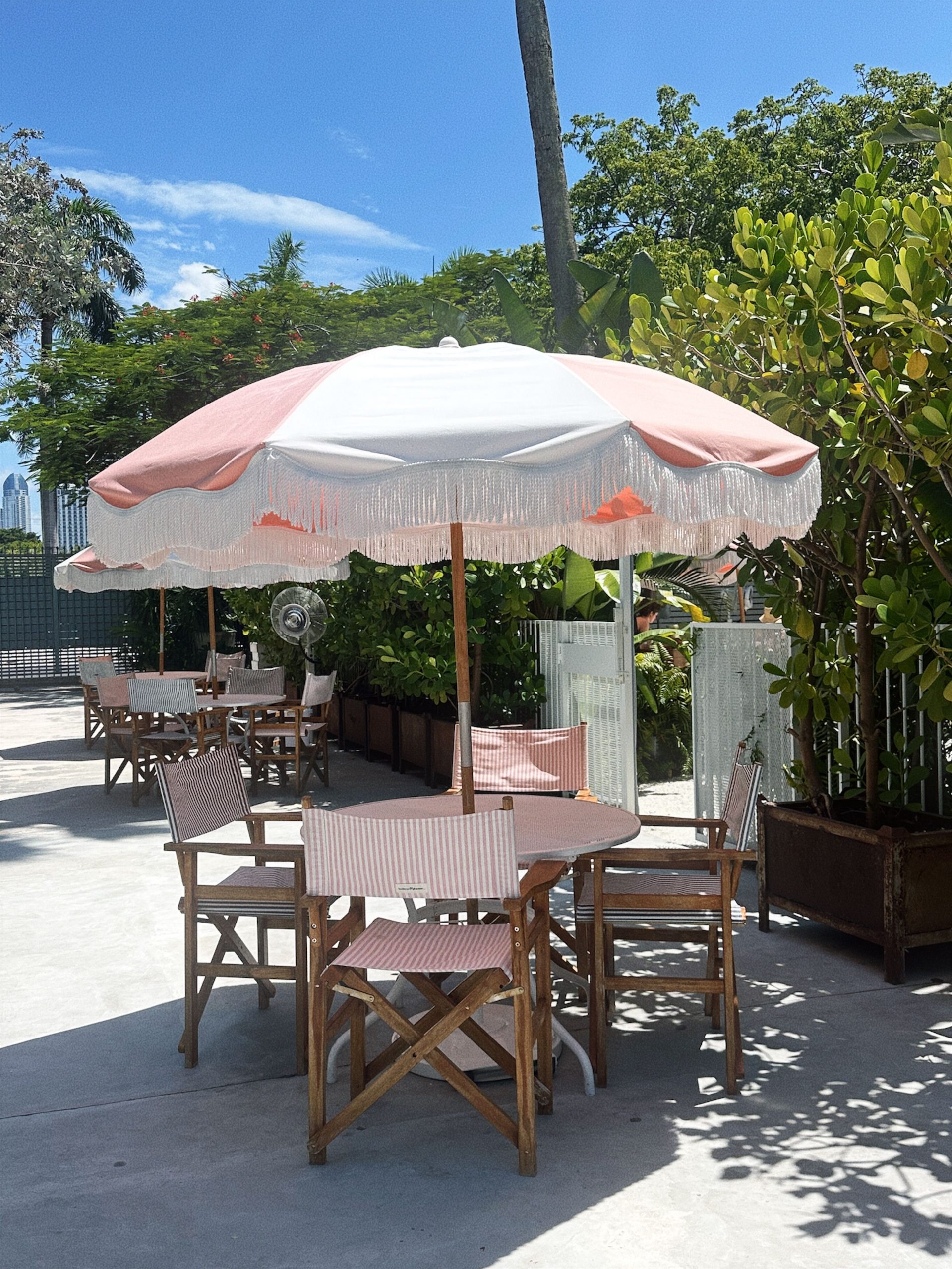 Charming outdoor patio scene with a pink and white umbrella under blue skies.