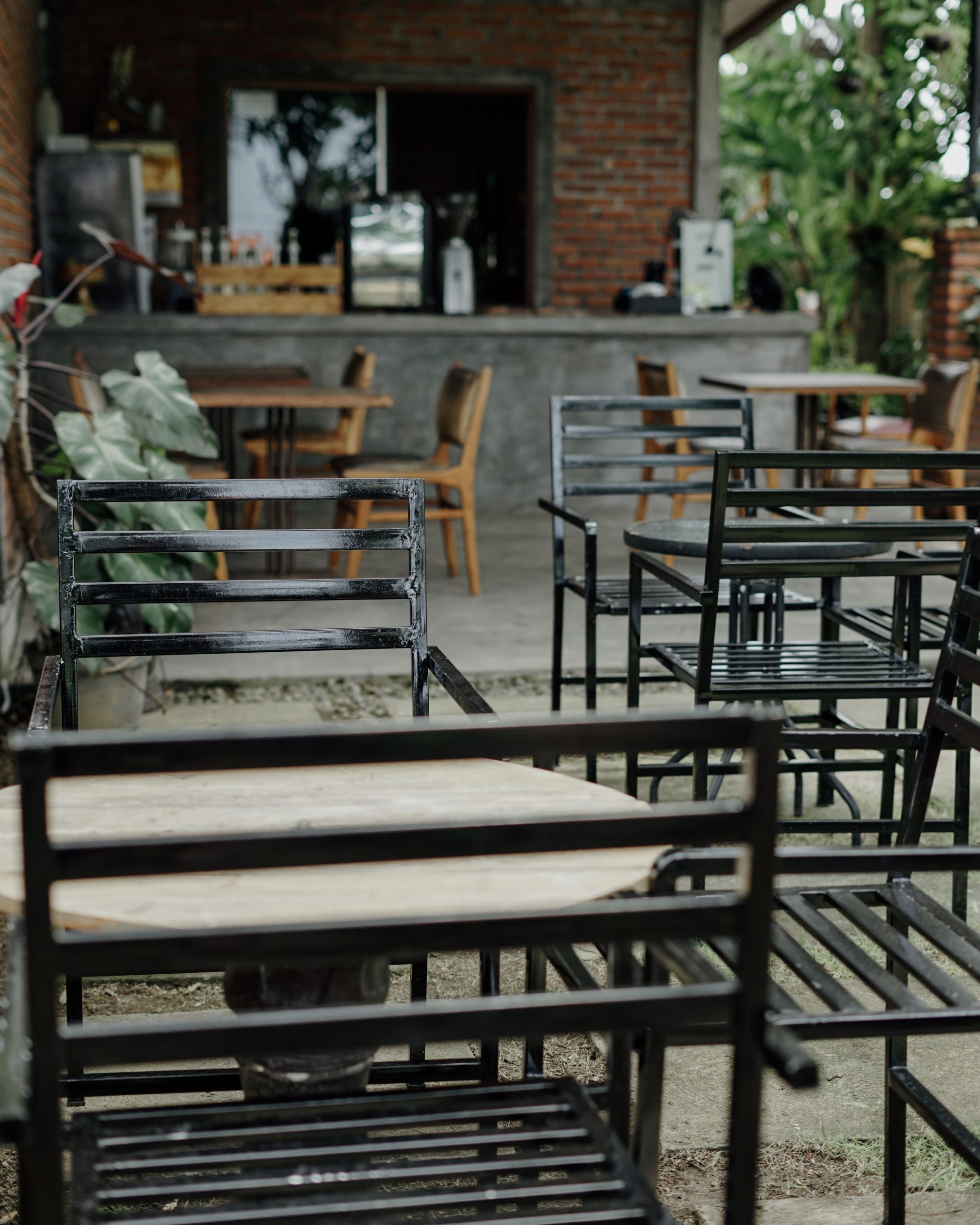 Charming outdoor patio seating with metal chairs and wooden tables at a cozy cafe, ideal for relaxing moments.