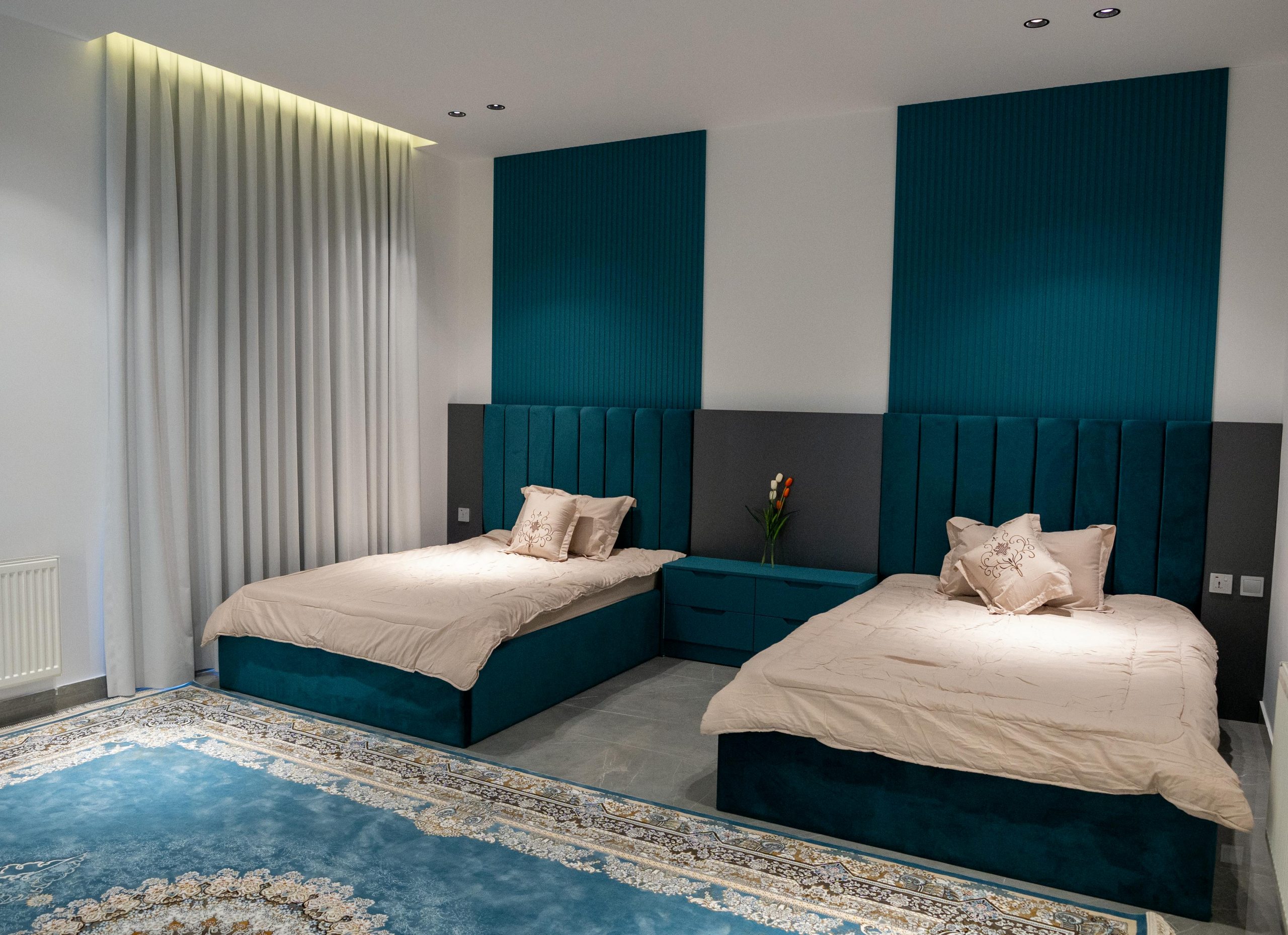 Chic hotel room featuring twin beds with teal accents and elegant decor.